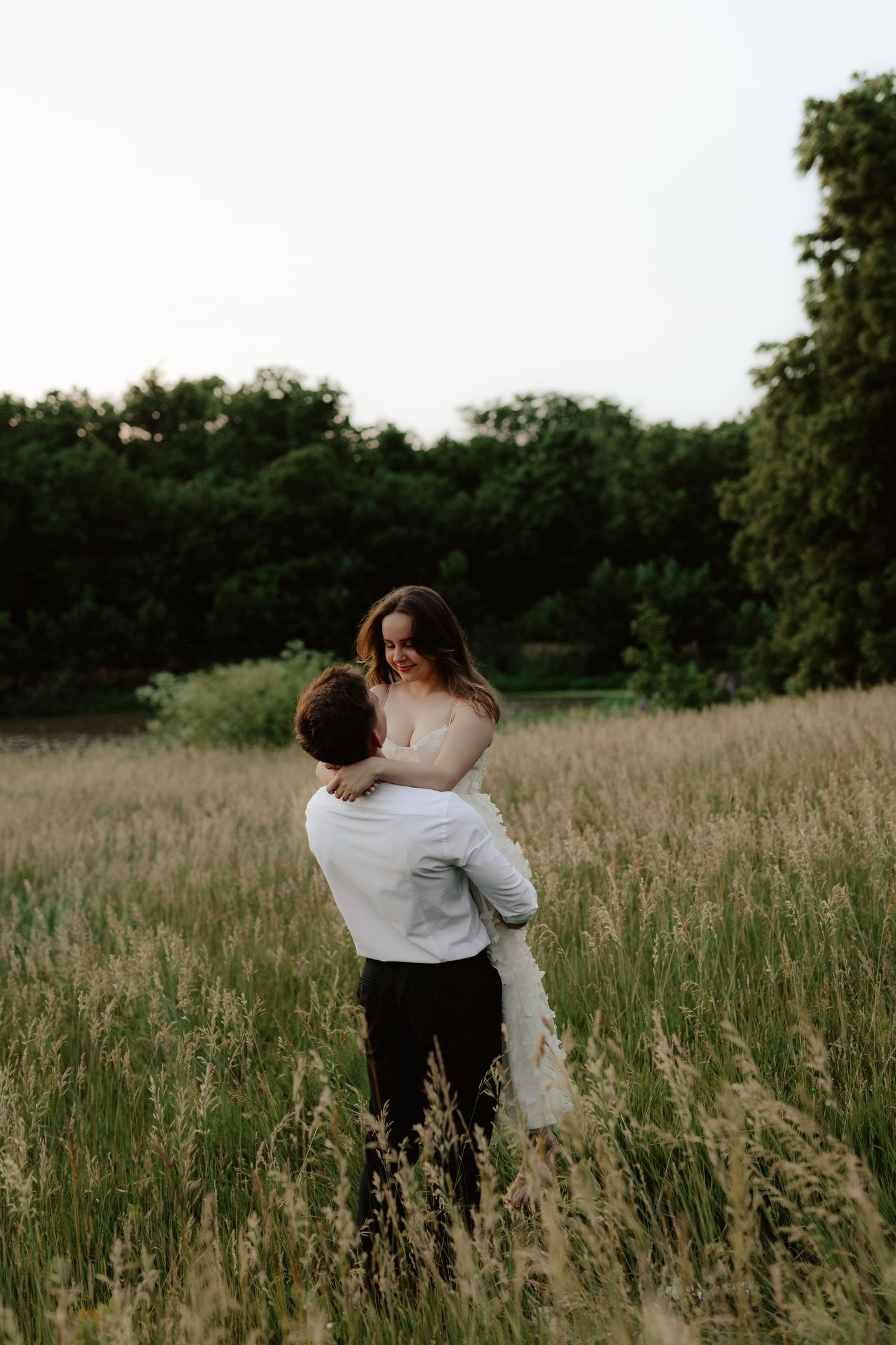 Beautiful couple sharing a romantic sunset moment during a proposal near a serene pond at summertime in Nebraska