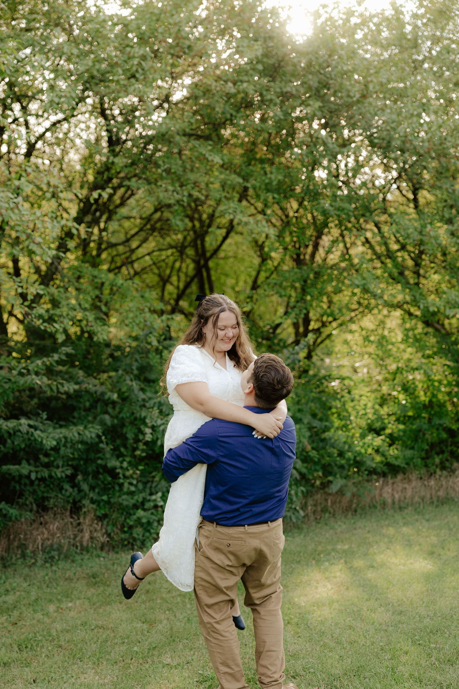 A couple walking hand in hand through lush green foliage on a summer afternoon.