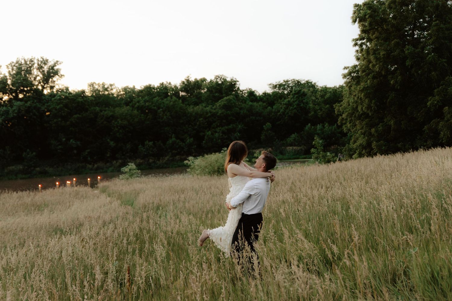 Beautiful couple sharing a romantic sunset moment during a proposal near a serene pond at summertime in Nebraska