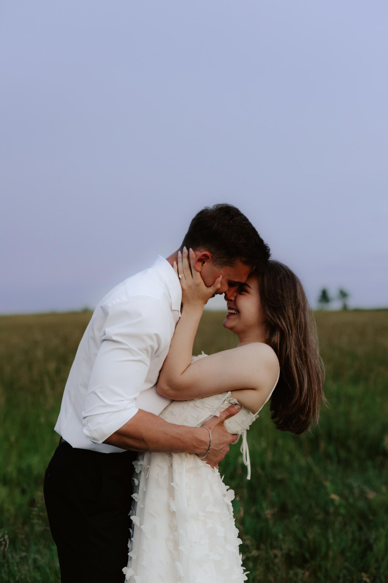 Beautiful couple sharing a romantic blue hour moment during a proposal near a serene pond at summertime in Nebraska