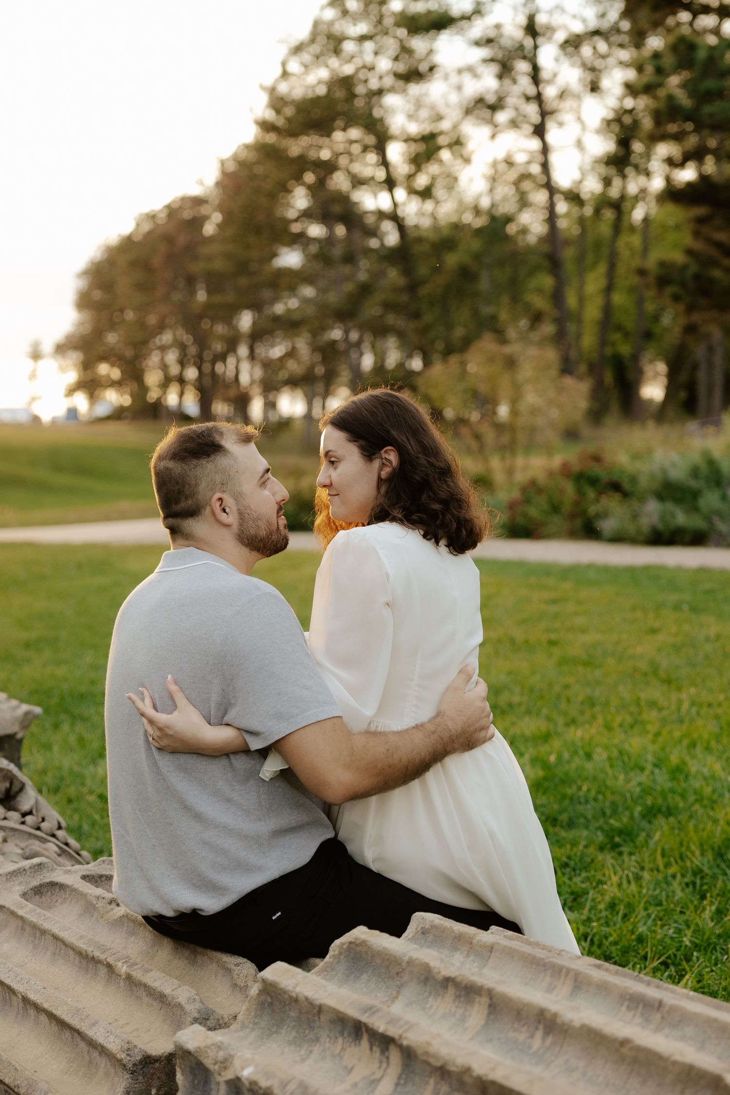 Couple shares romantic moment against stone pillars at sunset during outdoor wedding photoshoot.