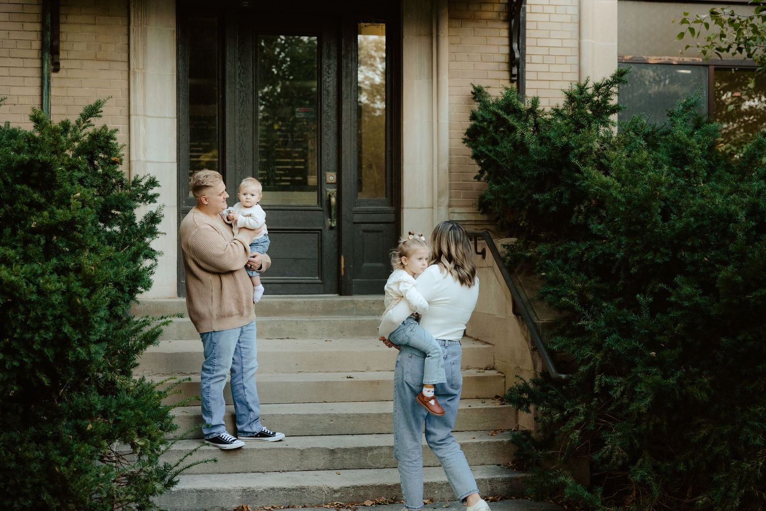 A family stands together on concrete steps outside a building during a family photo session.