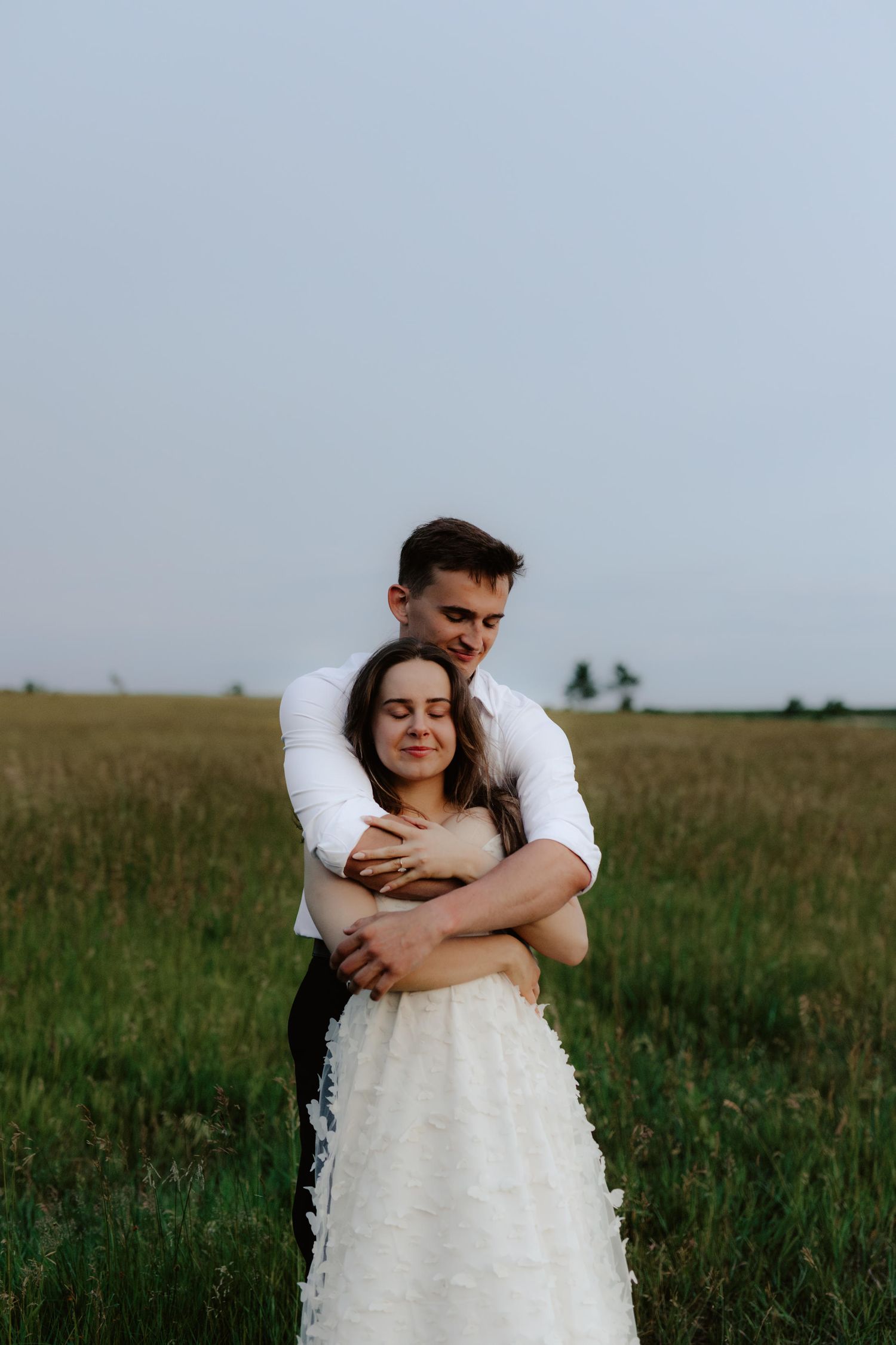 Beautiful couple sharing a romantic blue hour moment during a proposal near a serene pond at summertime in Nebraska