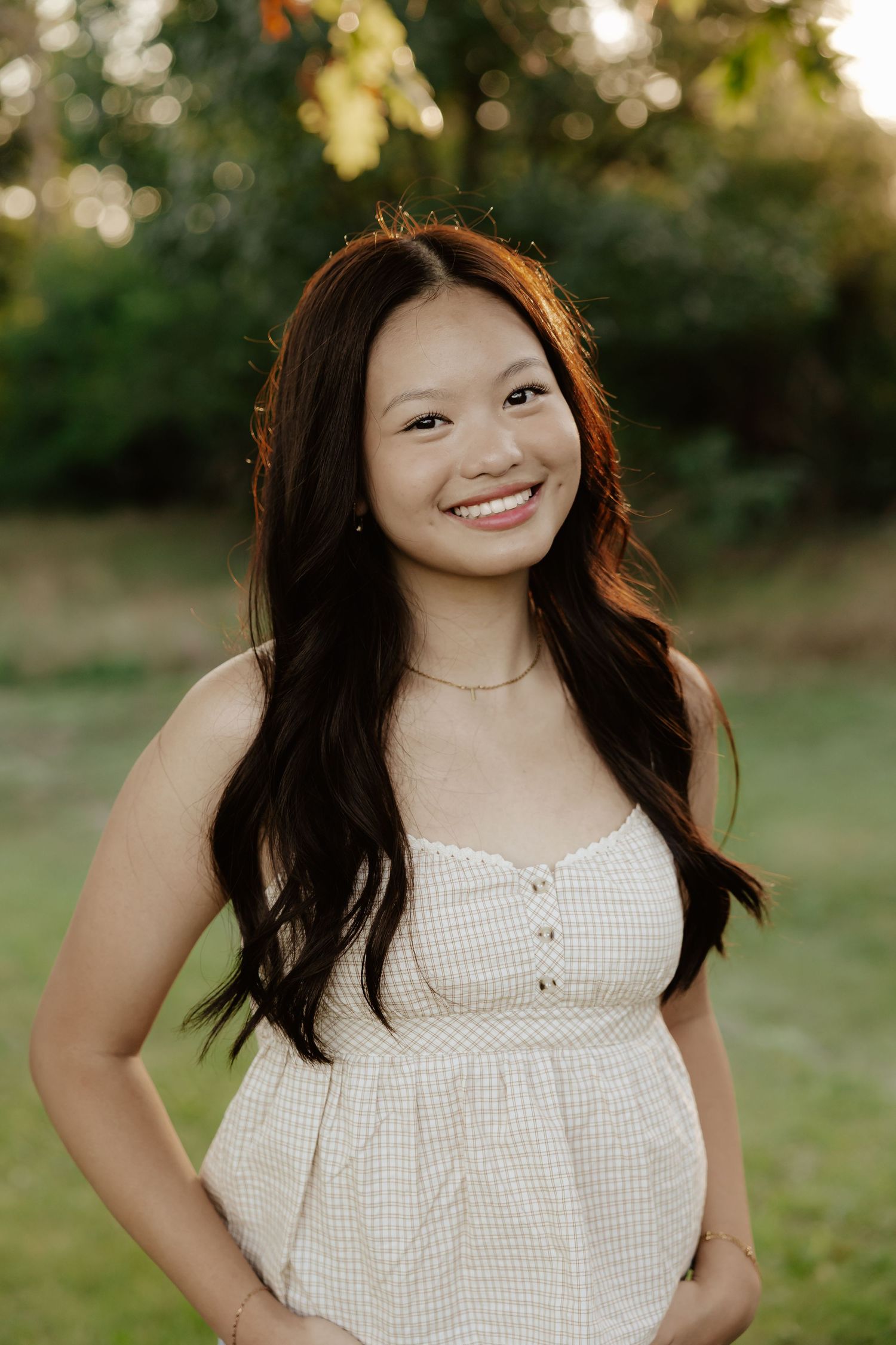 Senior photos taken outdoors at golden hour  wearing a white sleeveless top with a natural background.