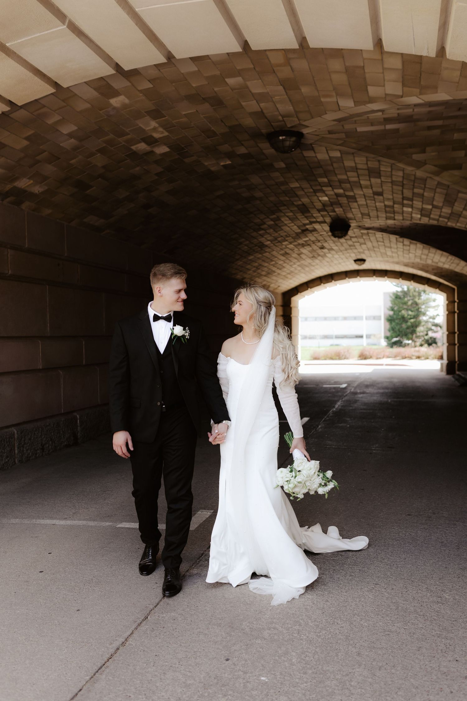 A wedding couple walks progressively through a stone brick tunnel at the Nebraska State Capitol building in Lincoln.