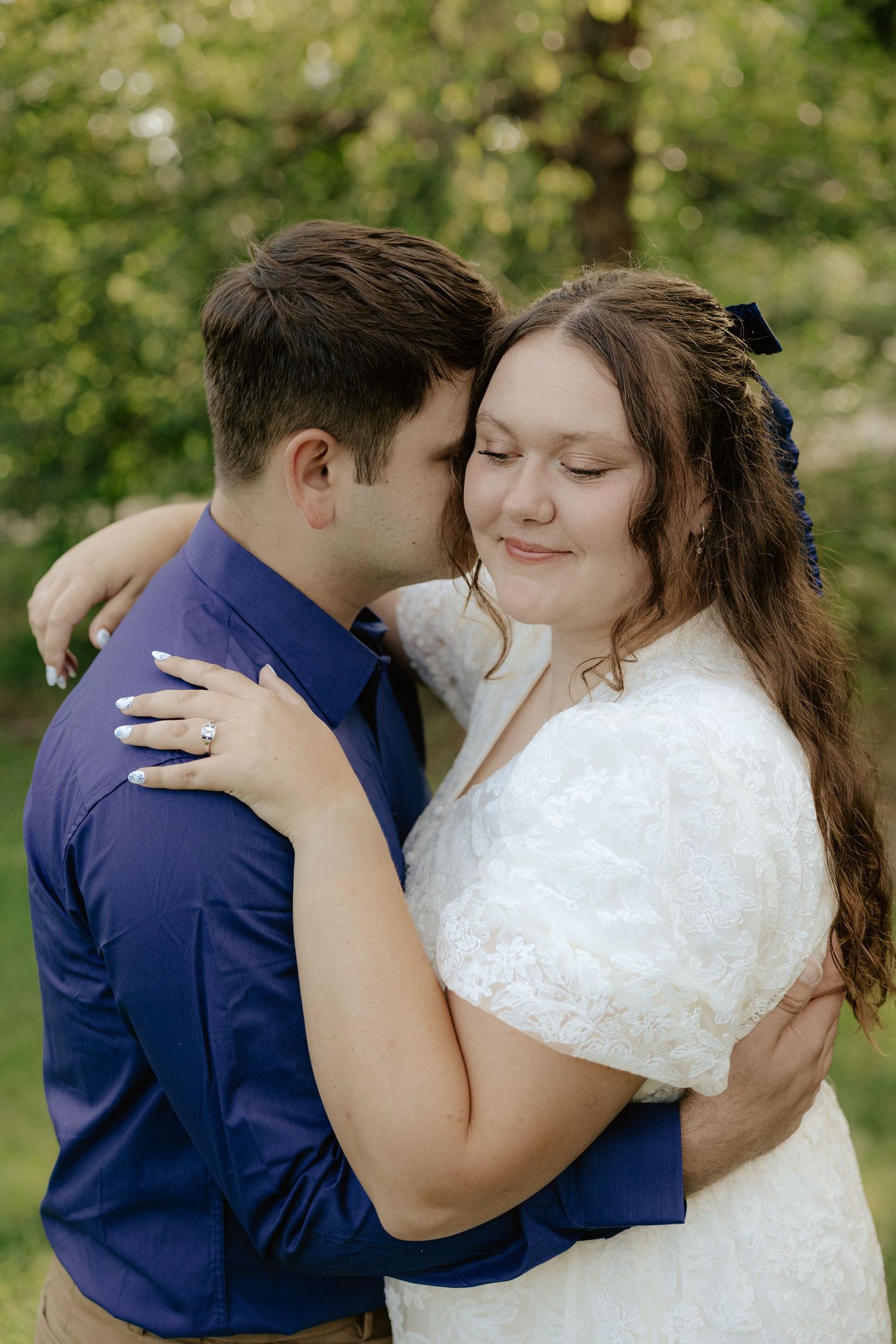 A romantic wedding couple in navy and white embrace in a garden setting, captured in a series of intimate moments.