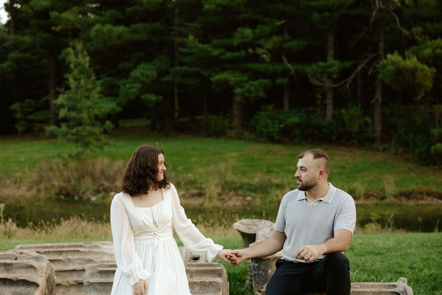 Couple shares romantic moment against stone pillars at sunset during outdoor wedding photoshoot.