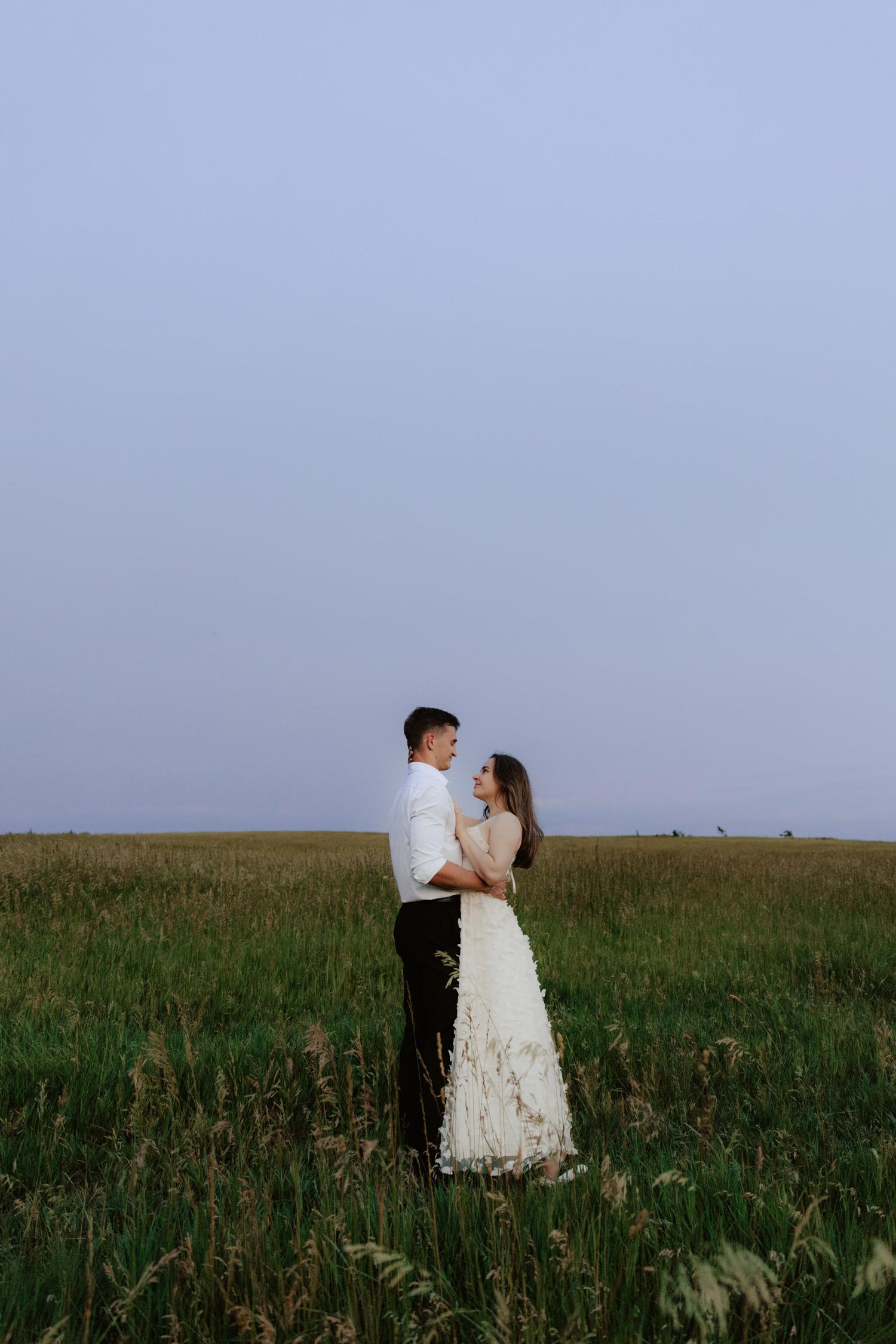 Beautiful couple sharing a romantic blue hour moment during a proposal near a serene pond at summertime in Nebraska