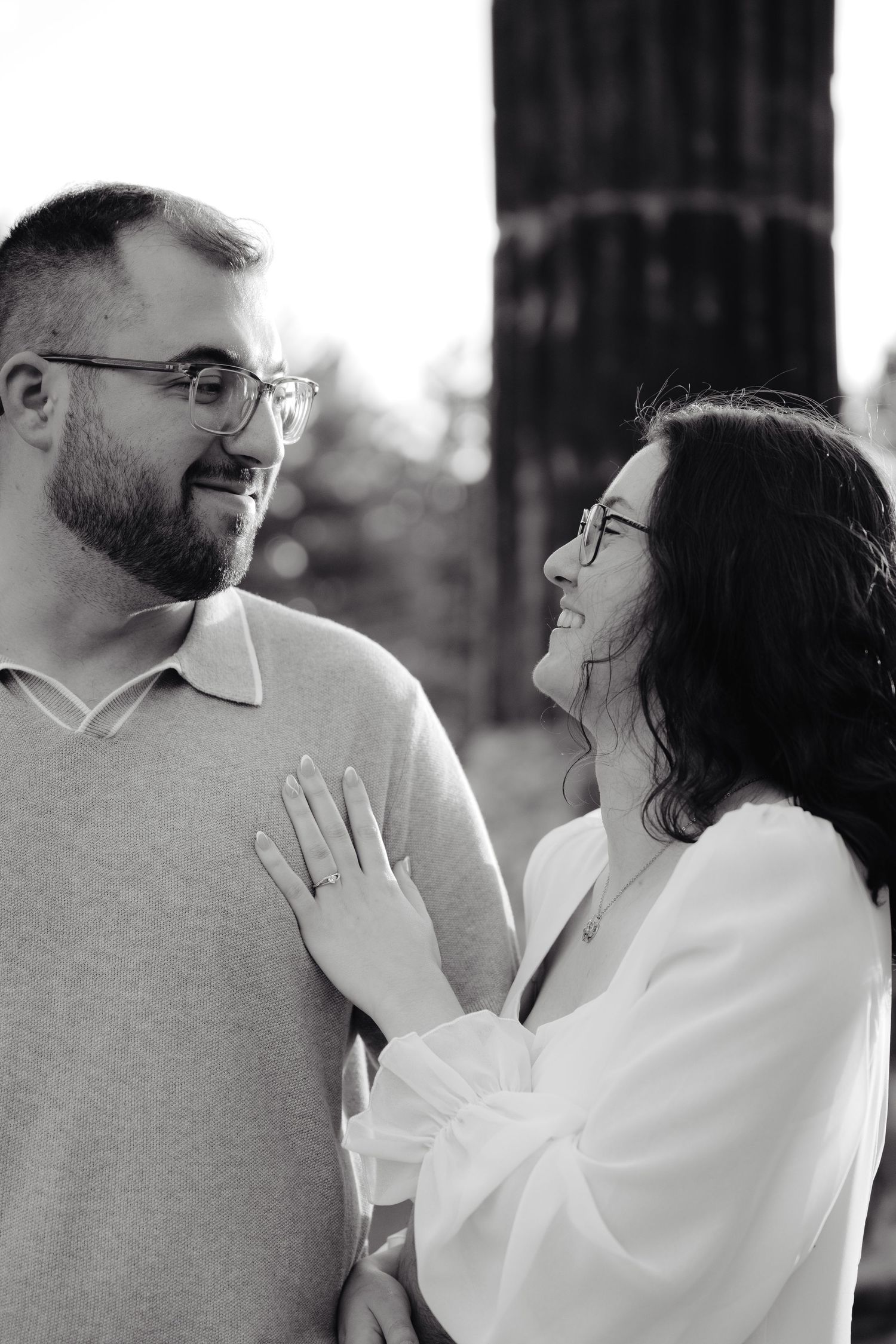 Couple shares romantic moment against stone pillars at sunset during outdoor wedding photoshoot.