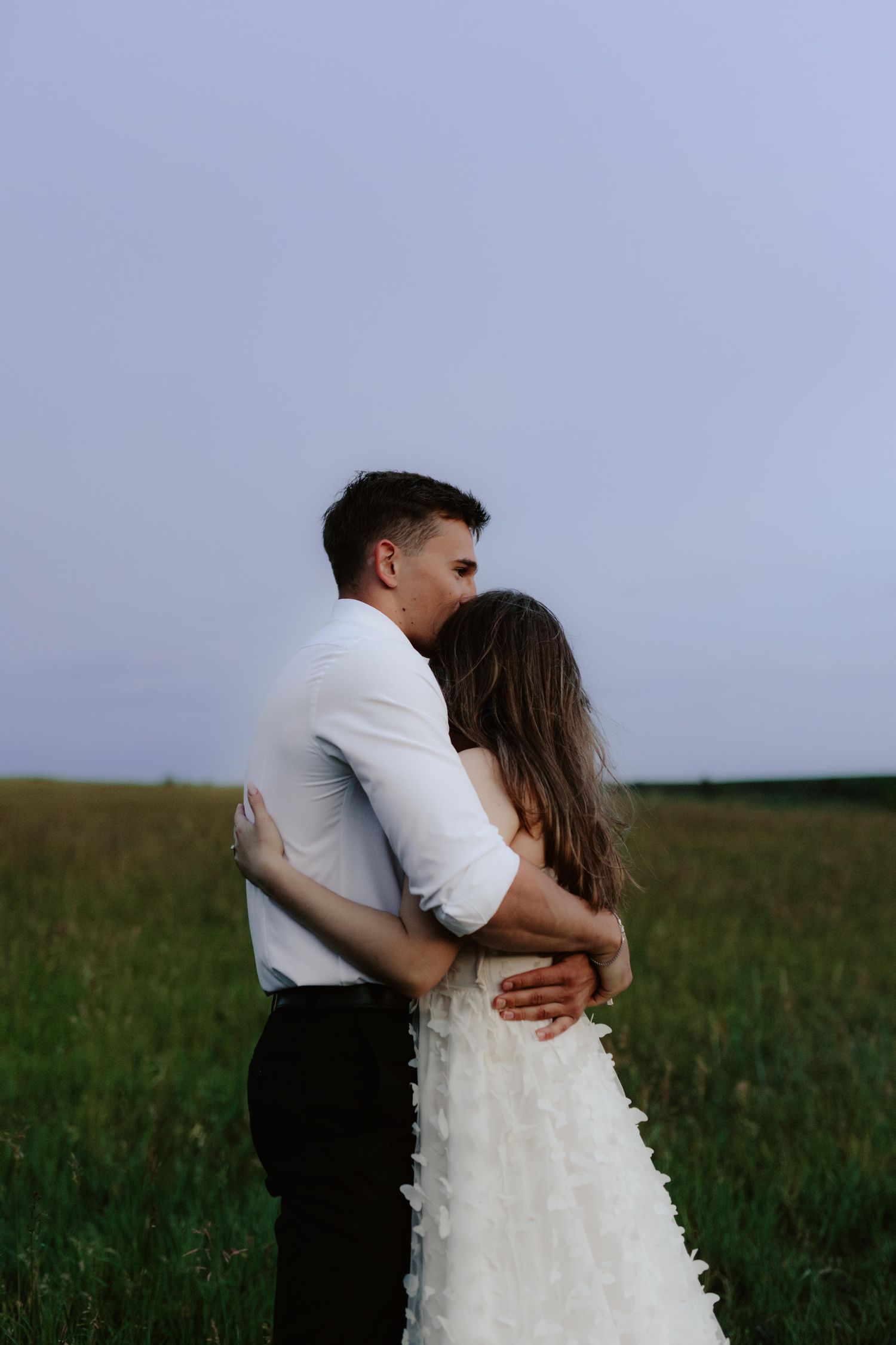 Beautiful couple sharing a romantic blue hour moment during a proposal near a serene pond at summertime in Nebraska
