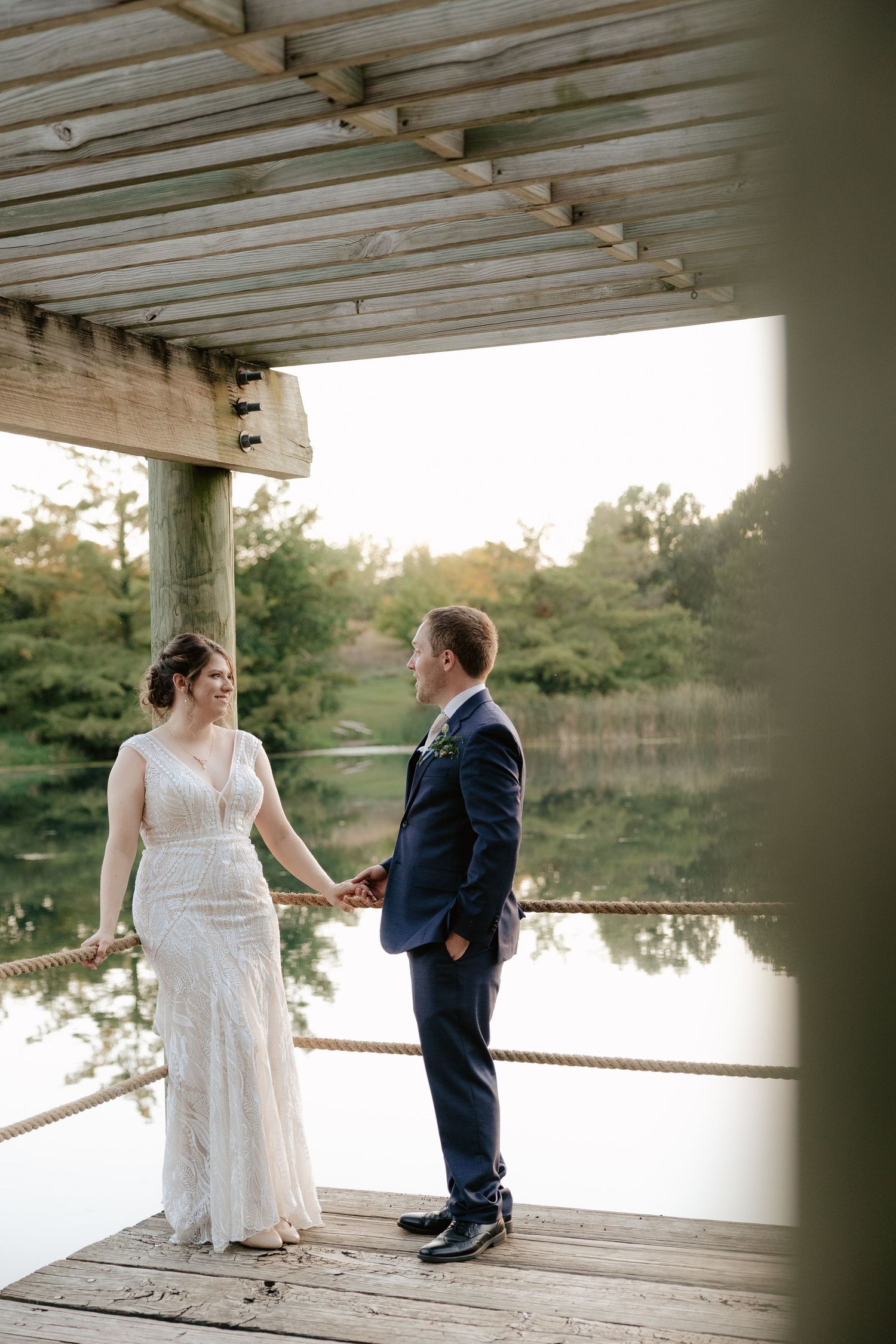 Couple shares intimate moments on a covered wooden deck overlooking a serene lake at sunset.