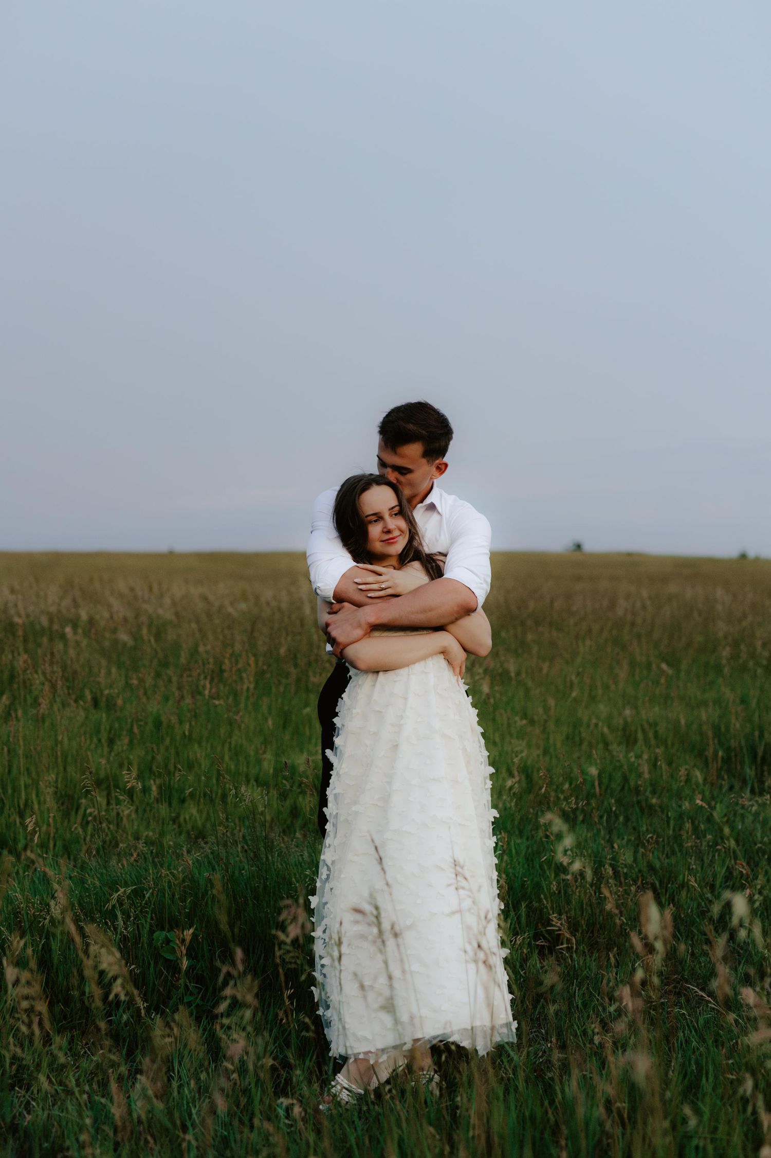 Beautiful couple sharing a romantic blue hour moment during a proposal near a serene pond at summertime in Nebraska