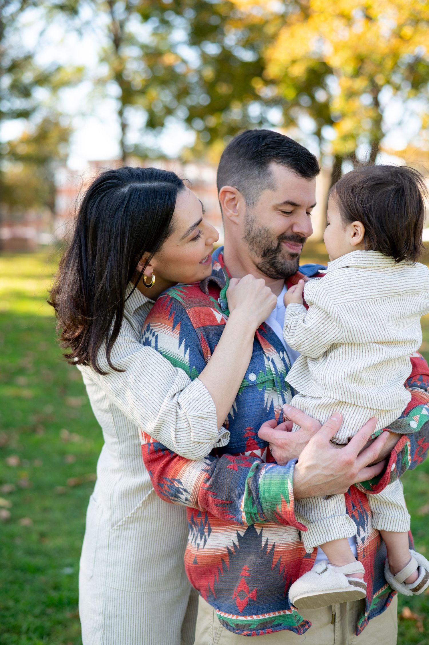 A family sharing a tender moment together in a park during autumn.