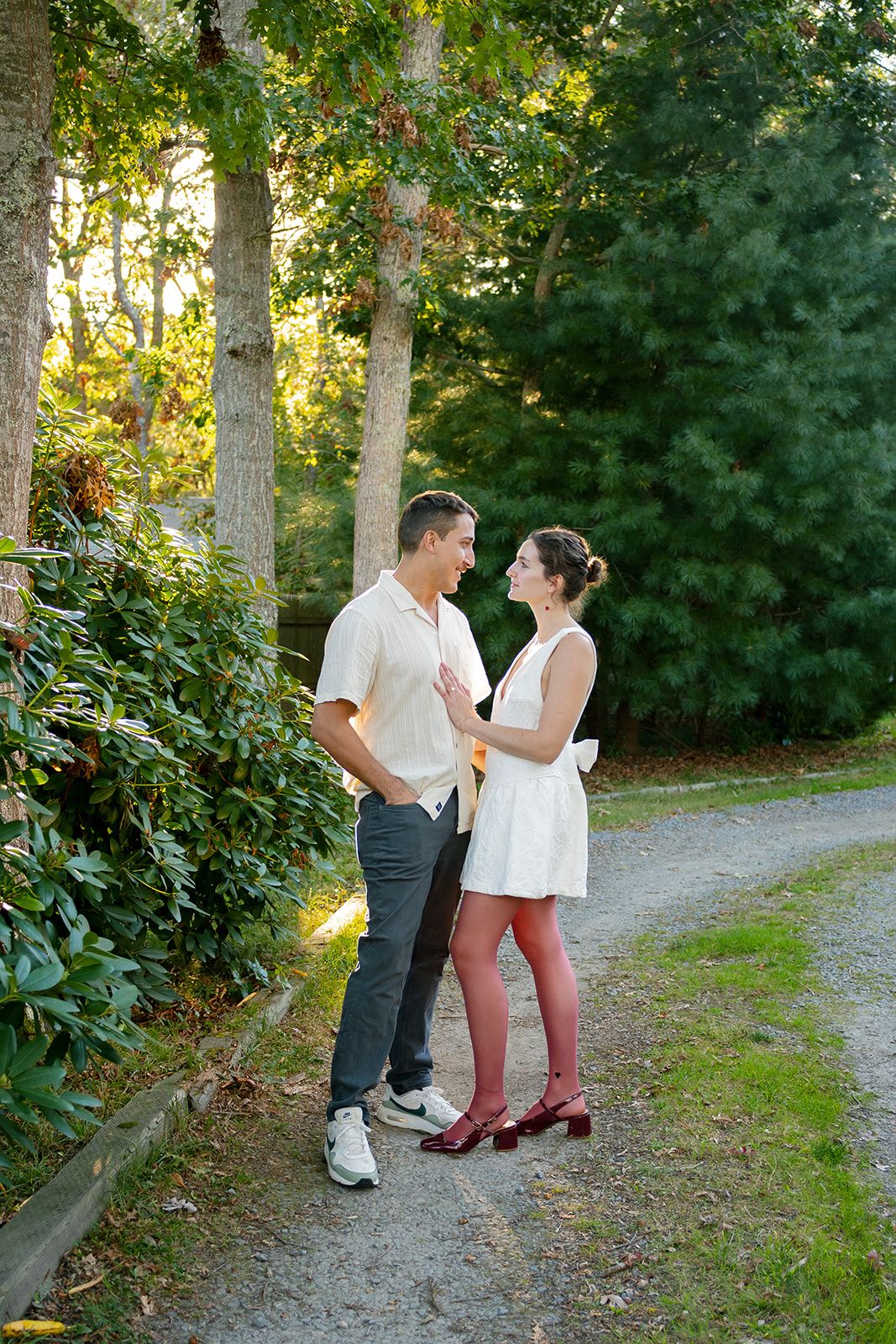 A couple dances together on a gravel path surrounded by lush green foliage on a sunny afternoon.