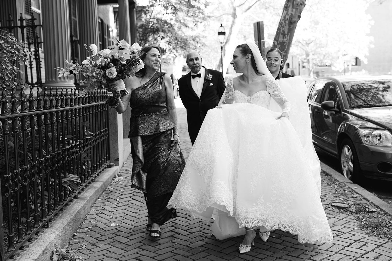 A black and white wedding photo sequence showing a bride and groom walking down a cobblestone street together.