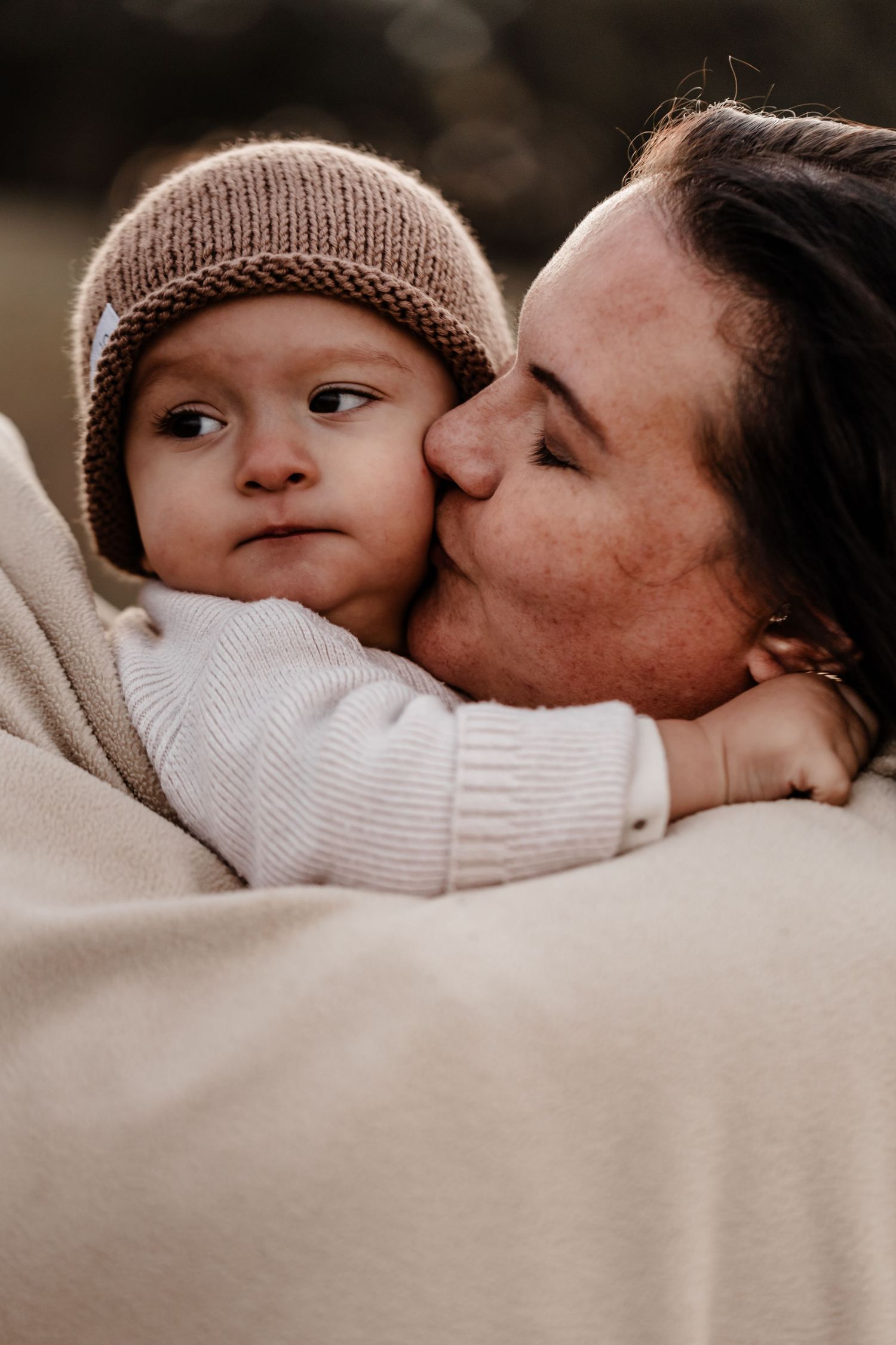 Tender moment between parent and baby wearing knit beanie in soft winter sweaters.