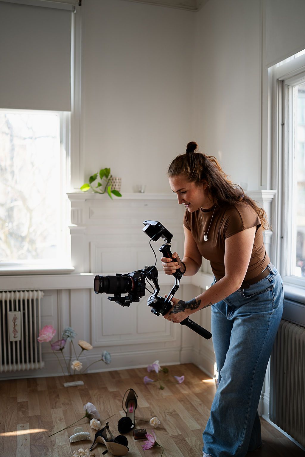 Photographer in casual attire demonstrating dynamic shooting positions in an indoor space.