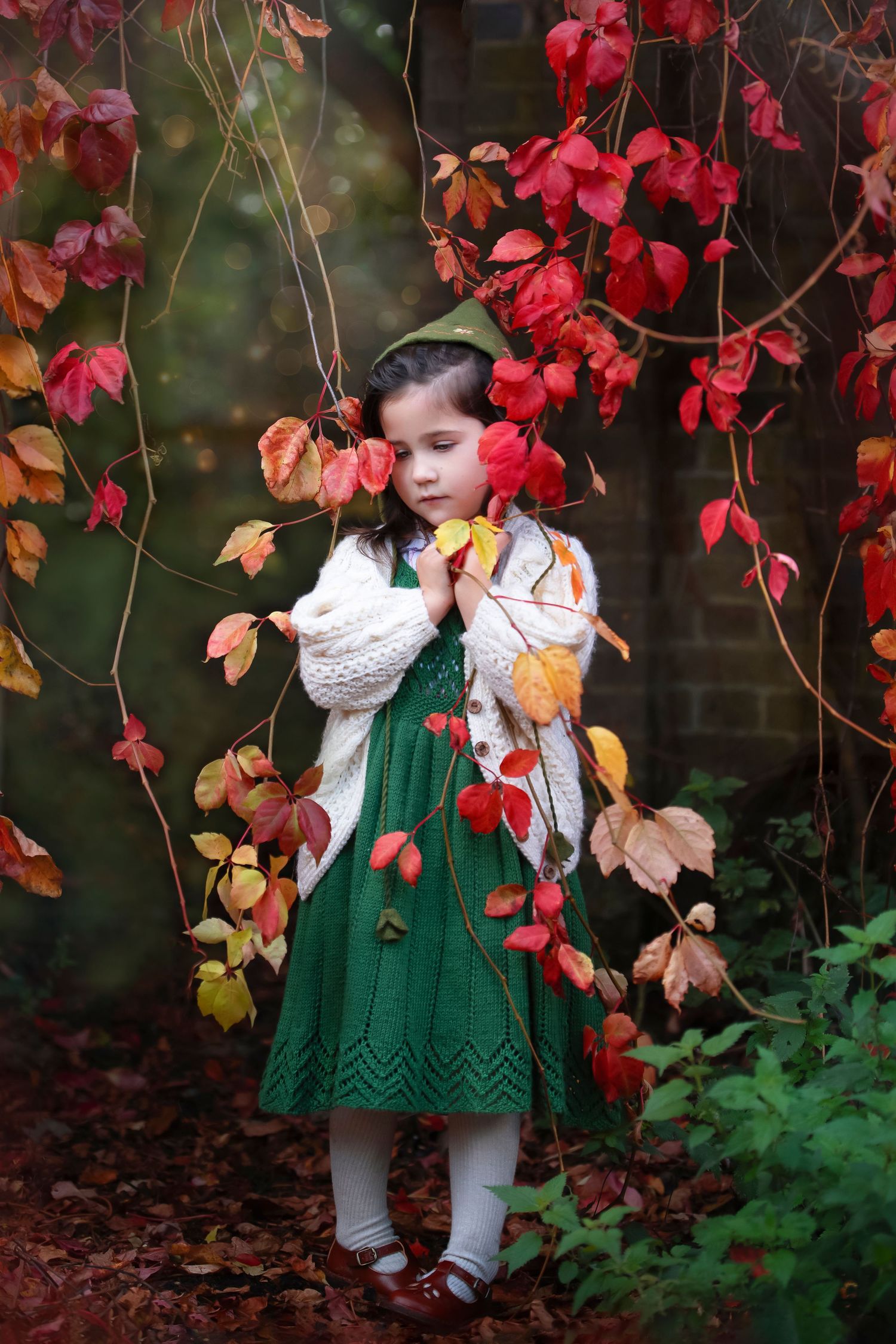 Seasonal autumn portrait showing a green knit dress against vibrant red fall foliage.