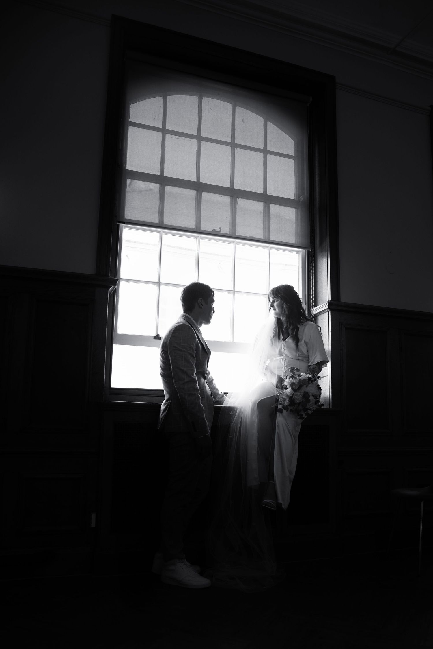 A newly wedded couple sat on the window ceil in the registry office that they just got married in