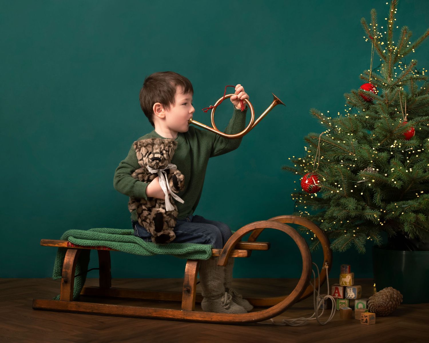 A vintage wooden sled decorated with holiday greenery and red berries against a dark teal backdrop.