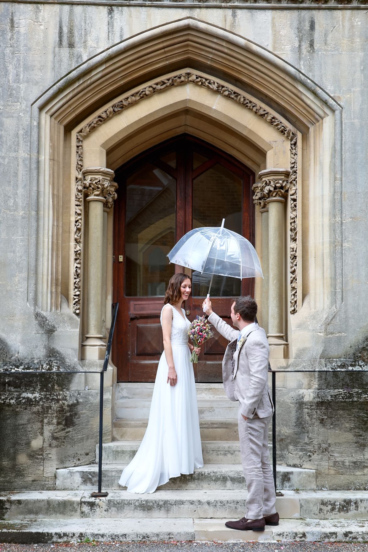 A couple shares a romantic moment in front of a Gothic stone archway during their wedding photoshoot.