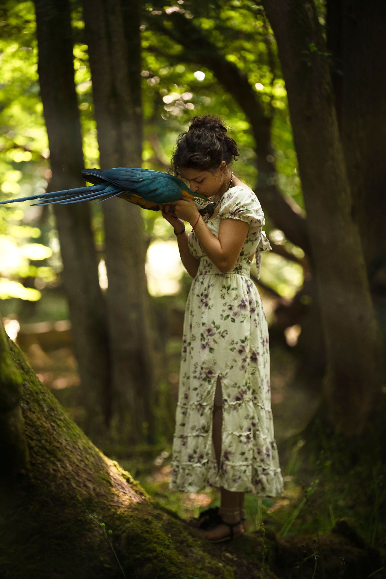 A child in a floral dress plays hide and seek among forest trees in dappled sunlight.