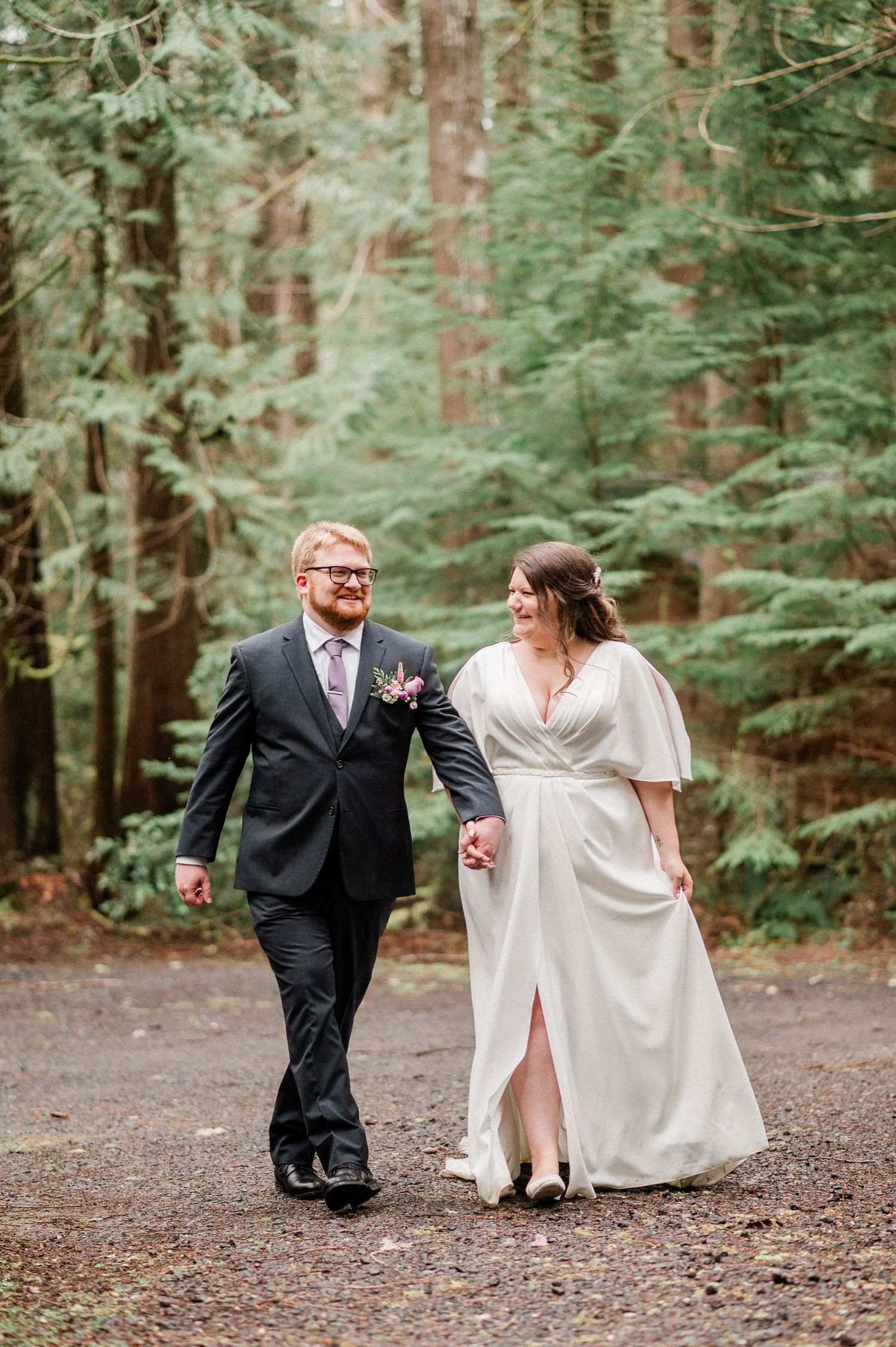 bride and groom walk hand in hand through a forest