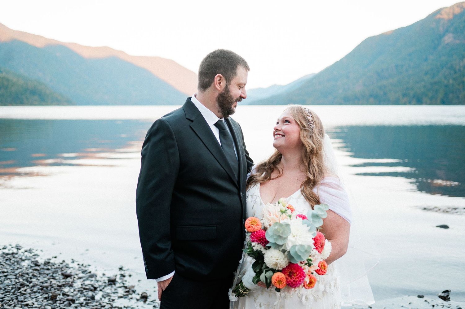 bride and groom looking at each other with Lake Crescent in background at sunrise