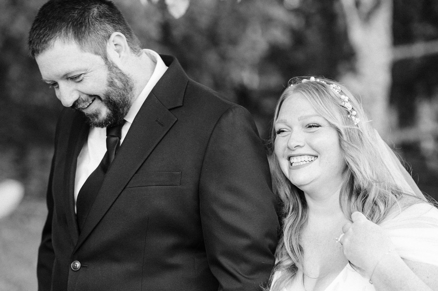 black and white photo of bride and groom laughing