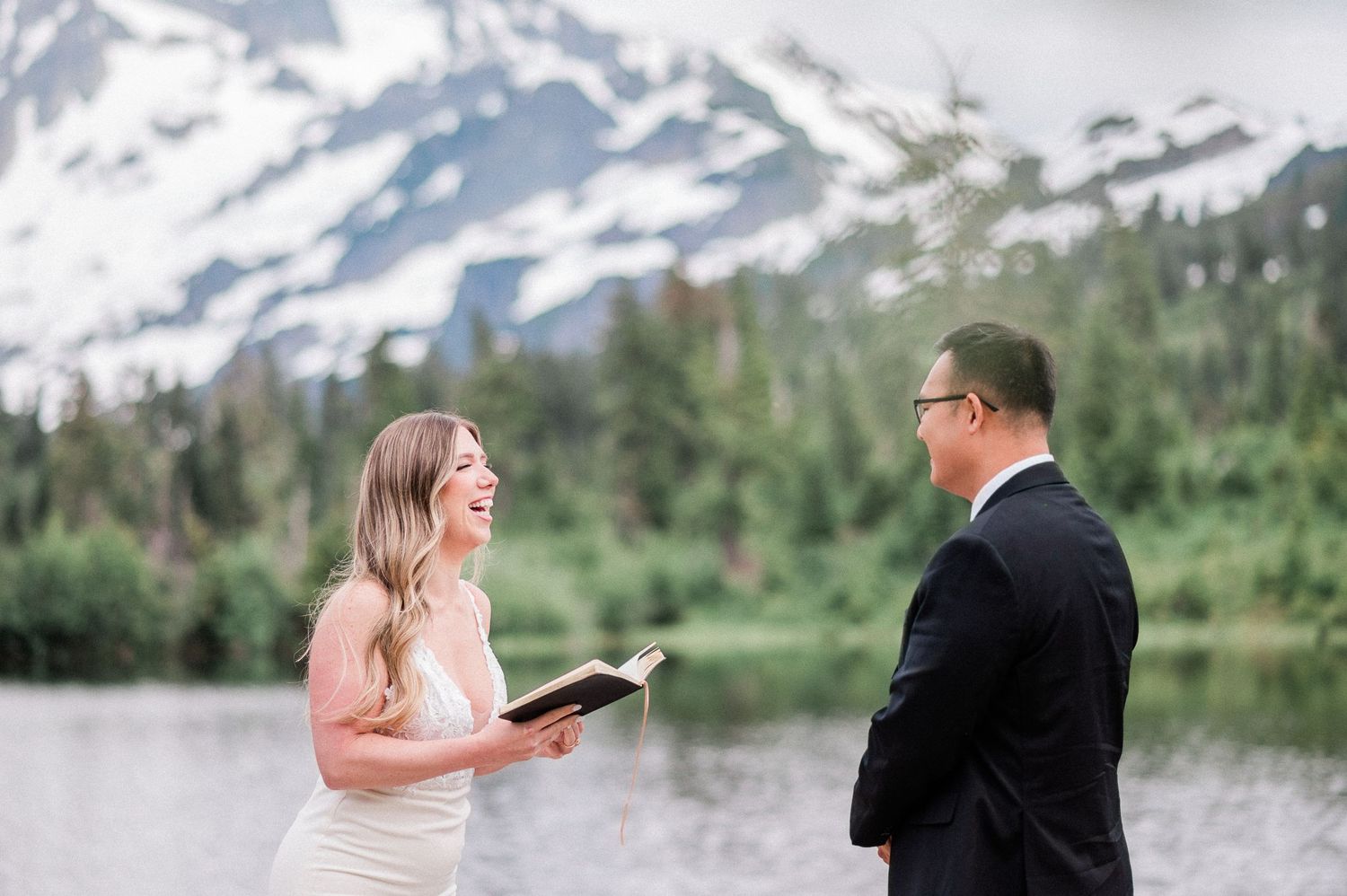 bride laughs while reading her vows with a snowcapped mountain behind her
