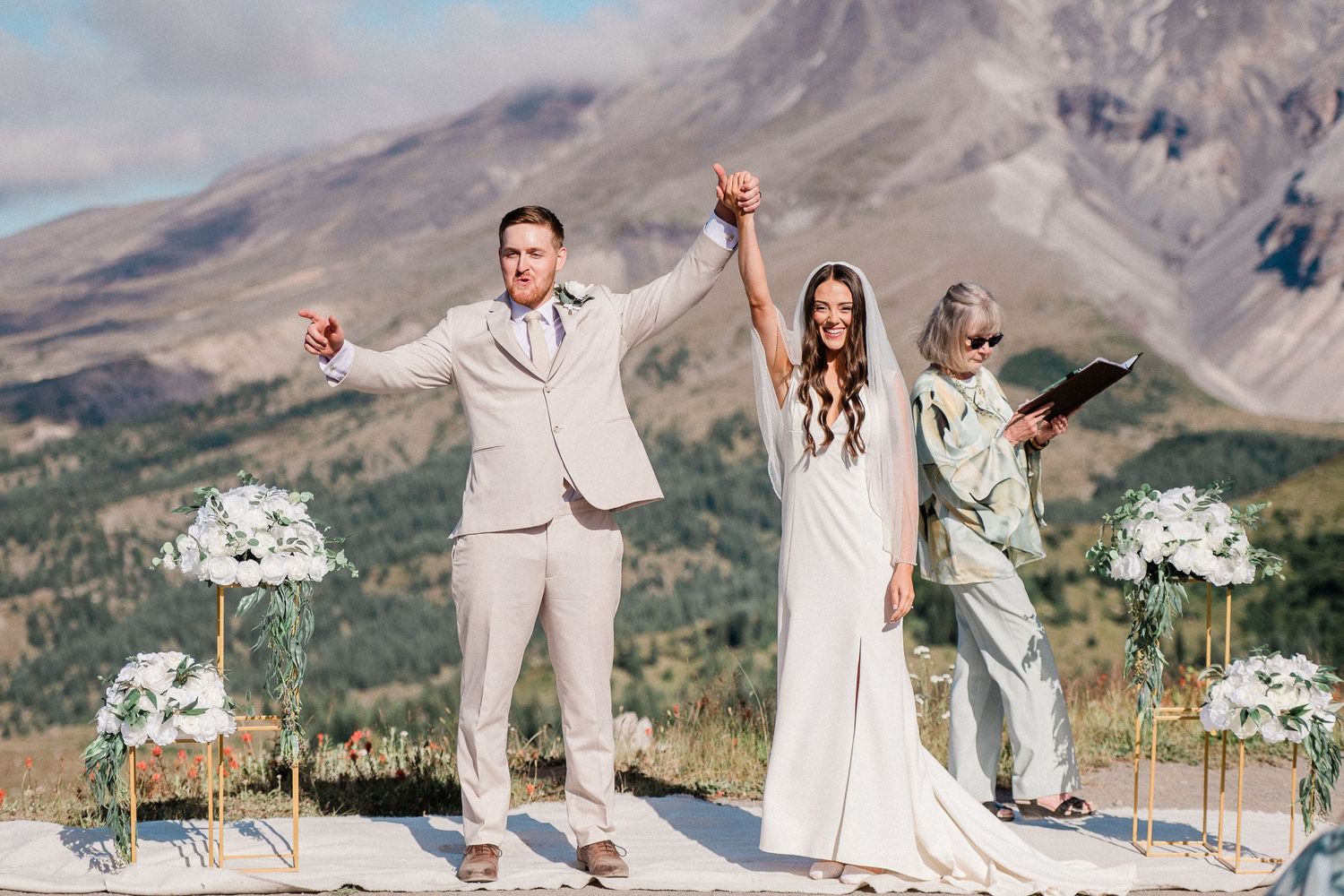 bride and groom celebrate getting married with Mt. St. Helens in the background. Photo by Washington Elopement Photographer