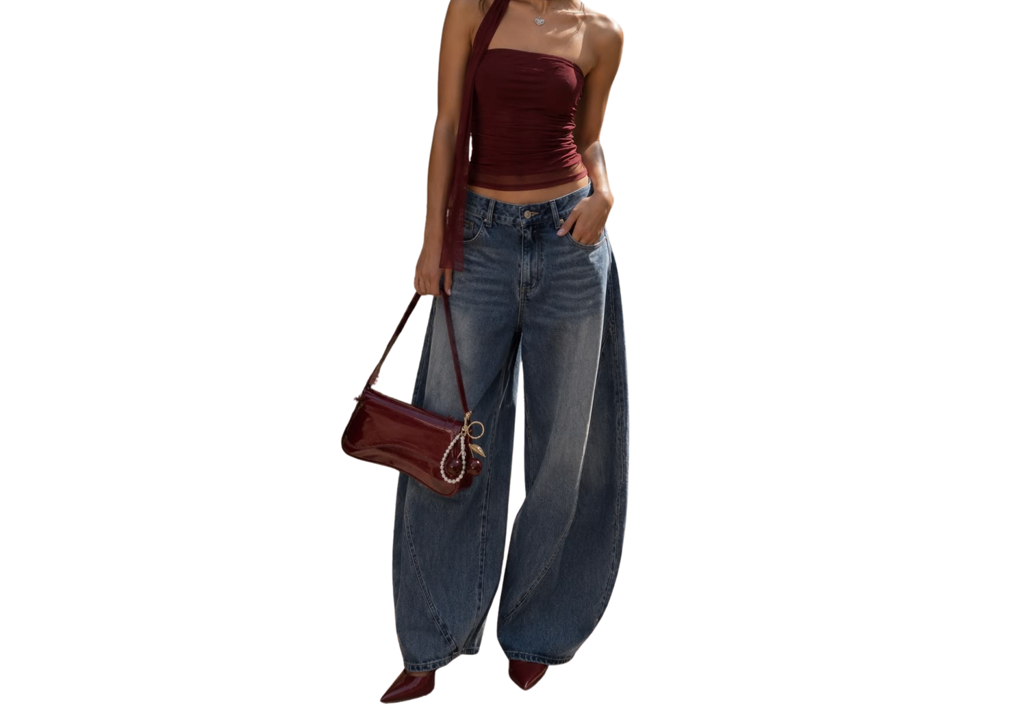 Woman wearing a dark red crop tube top, wide-leg blue jeans, and carrying a brown shoulder bag.