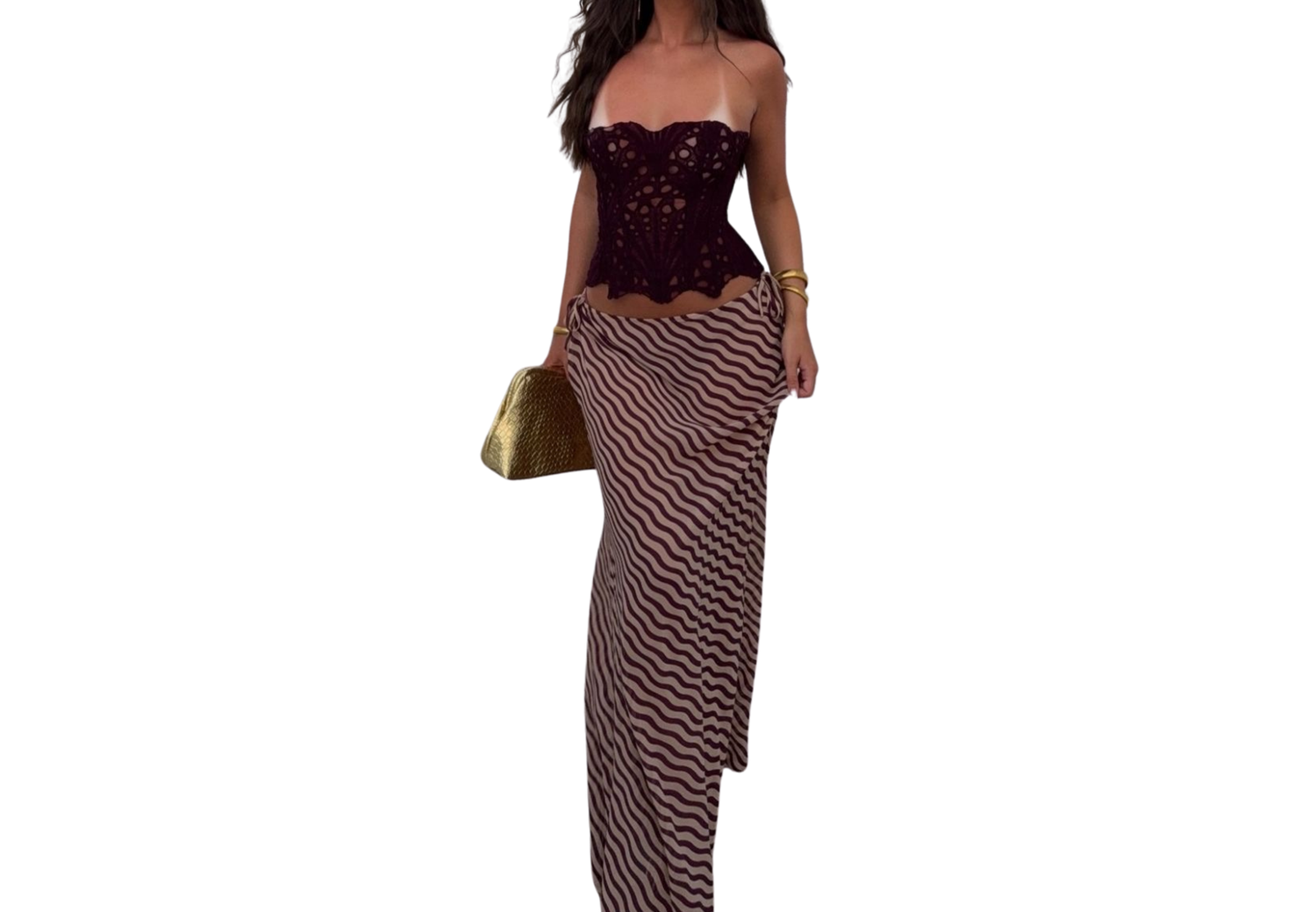 Woman wearing a strapless sequin burgundy corset top with striped maxi skirt and gold clutch bag.