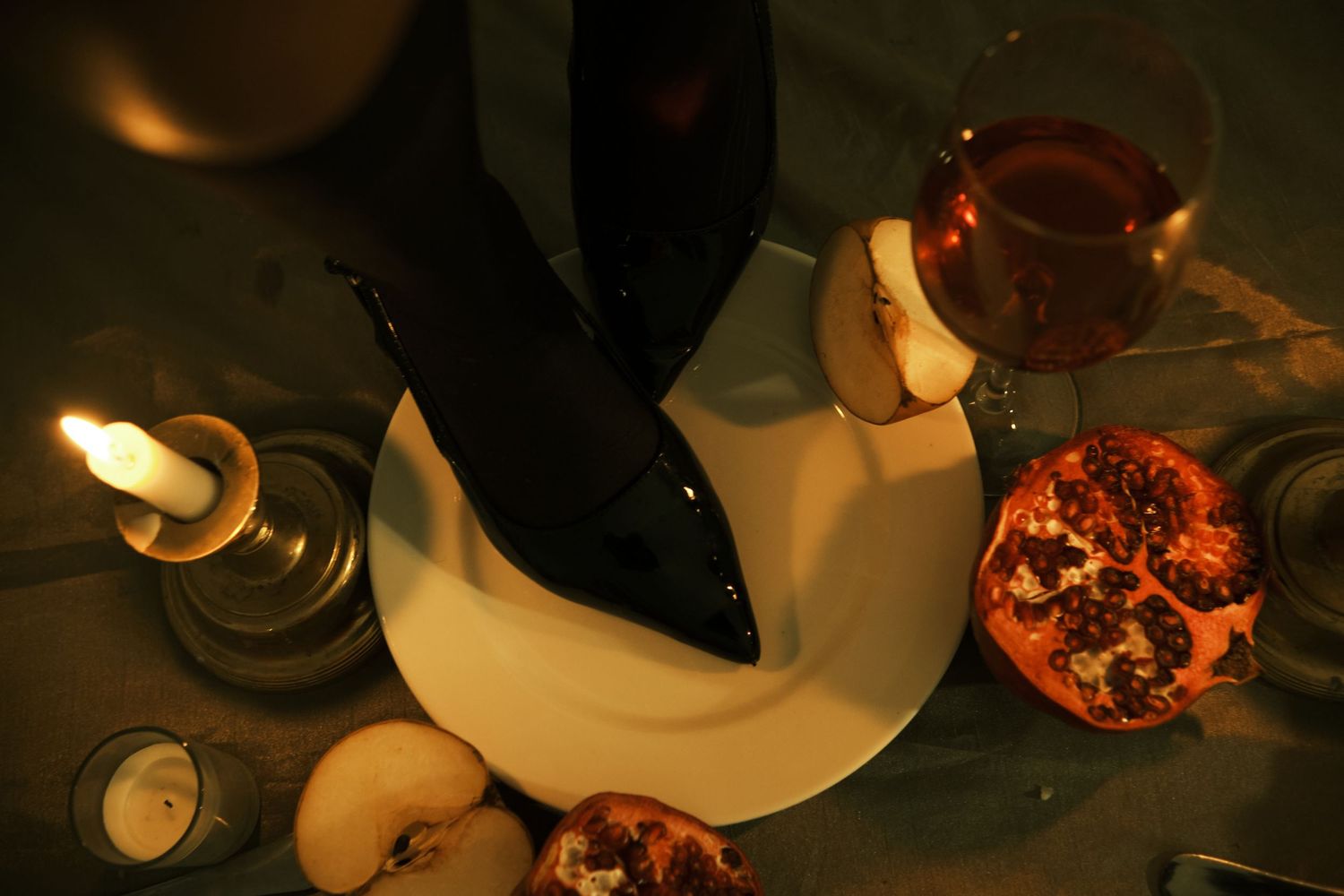 Glowing candles illuminate a cozy table setting with warm ambiance in a dark room.