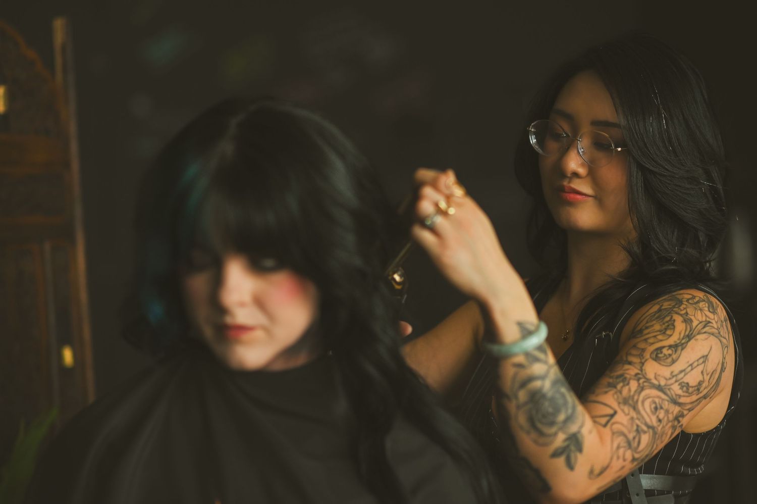 A series of dark moody portraits showing someone with tattoos and dark hair in dramatic lighting.