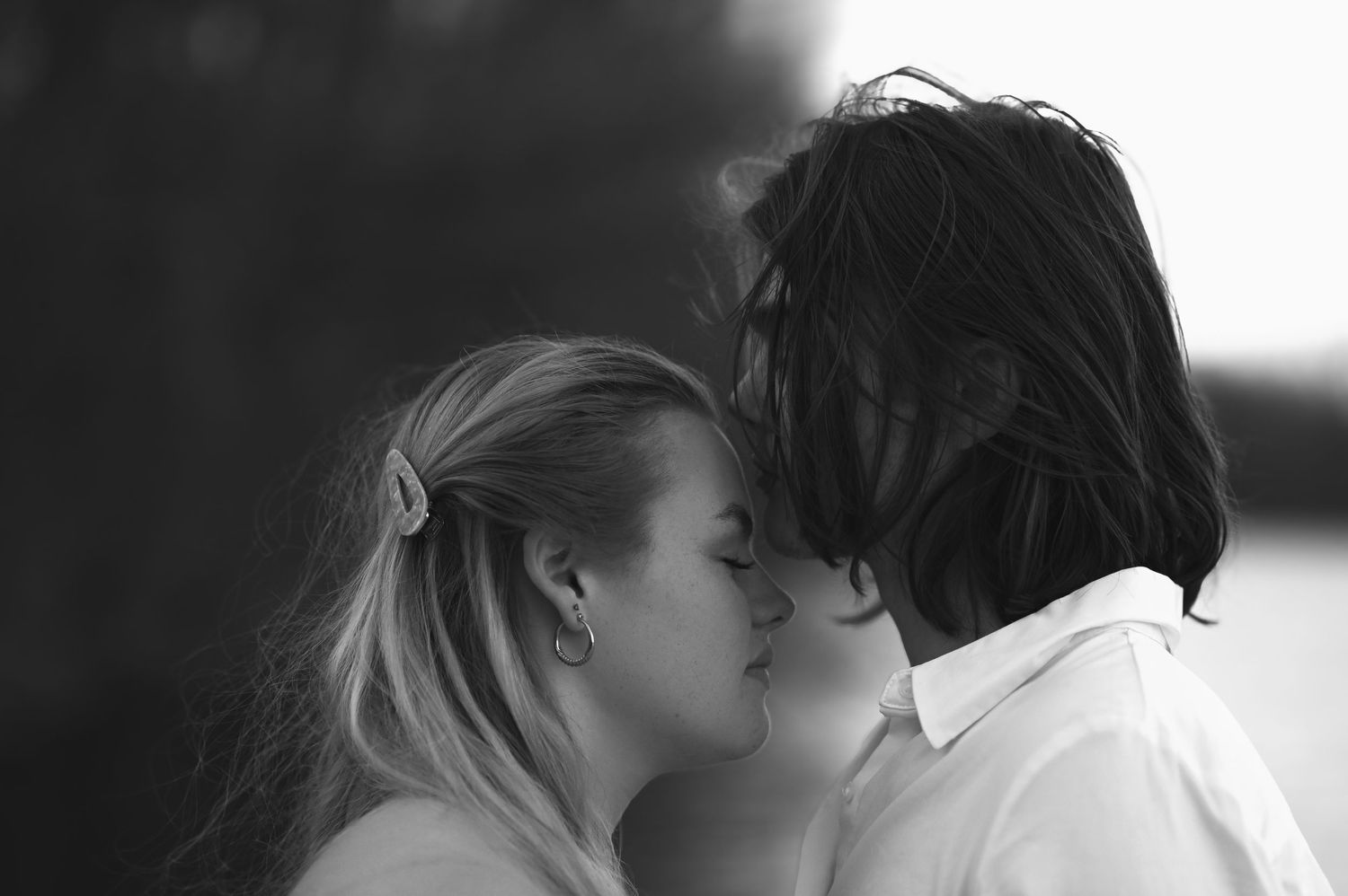 A romantic couple embraces and kisses in black and white silhouette against a light background.