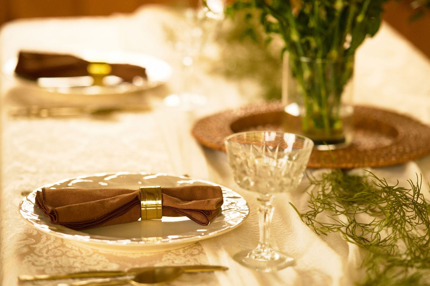 Elegant table setting with crystal glasses, white flowers, and soft candlelight creating a romantic dining atmosphere.