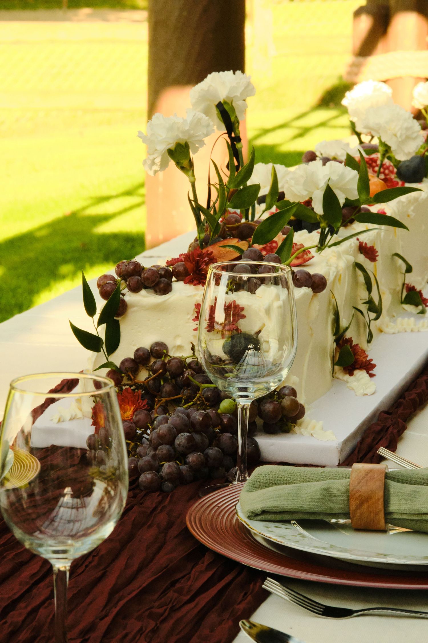 Elegant table setting with white calla lilies, red berries, and purple grapes on a dark brown textured tablecloth.