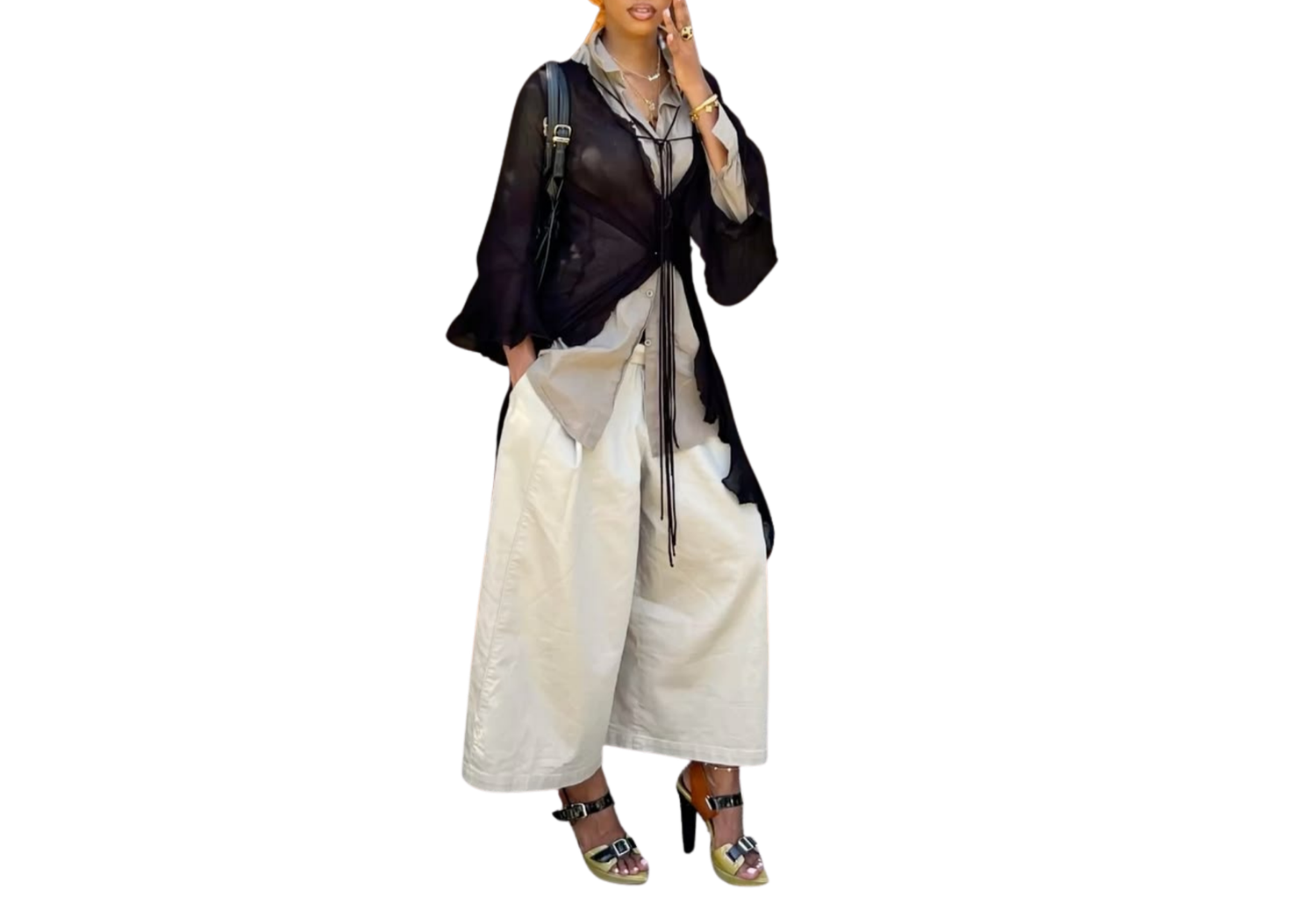 Woman in black sheer kimono jacket with wide-leg white pants and embellished heels.