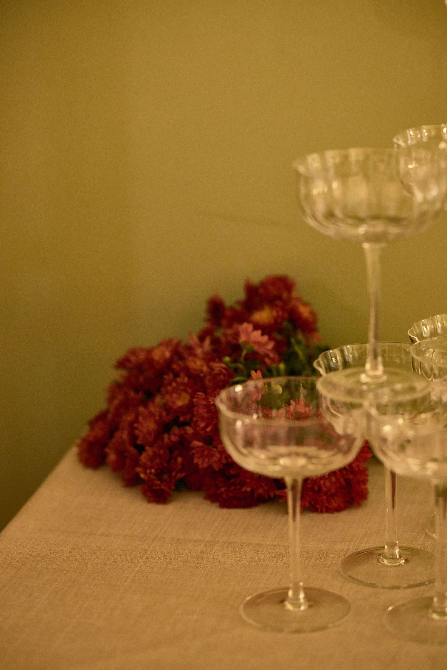 Crystal wine glasses and burgundy flowers arranged on an elegant table setting.