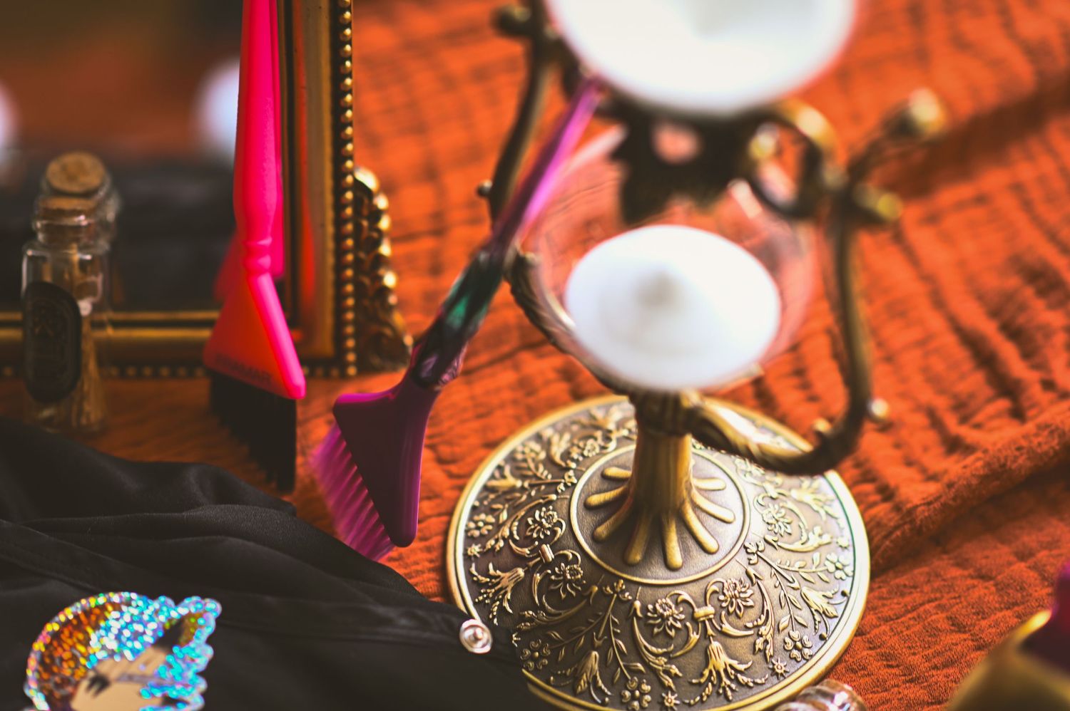 Detailed view of ornate golden Tibetan tingsha cymbals with decorative patterns on a red textured surface.