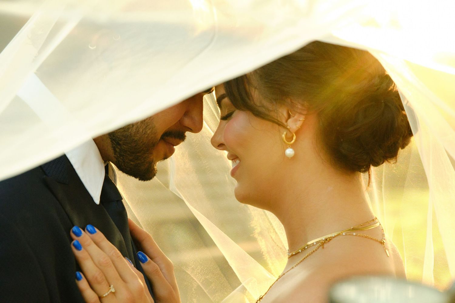 Intimate wedding moment captured under a flowing white veil.
