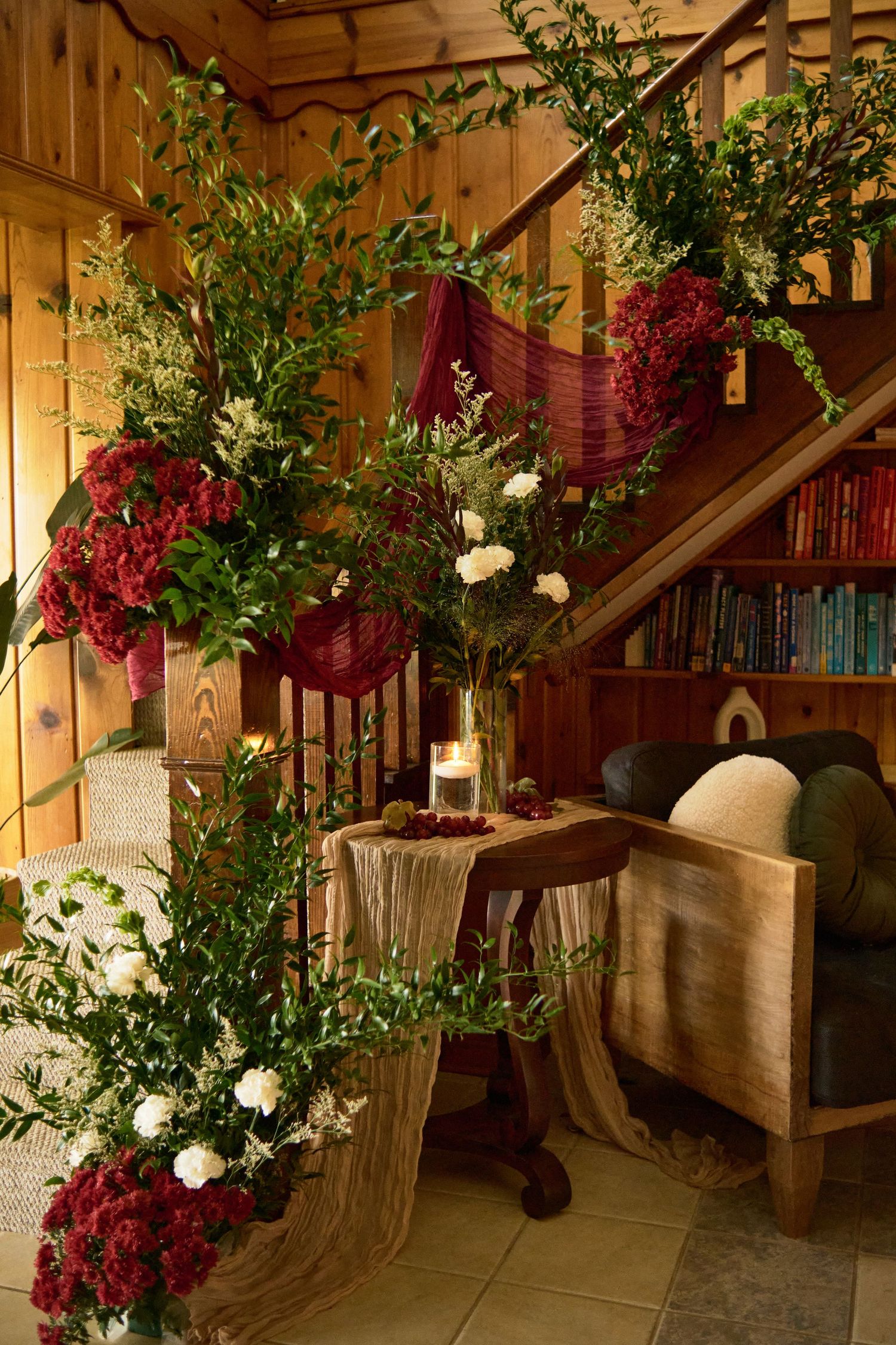 Elegant floral arrangement with red and white flowers decorating a wooden staircase near a bookshelf.