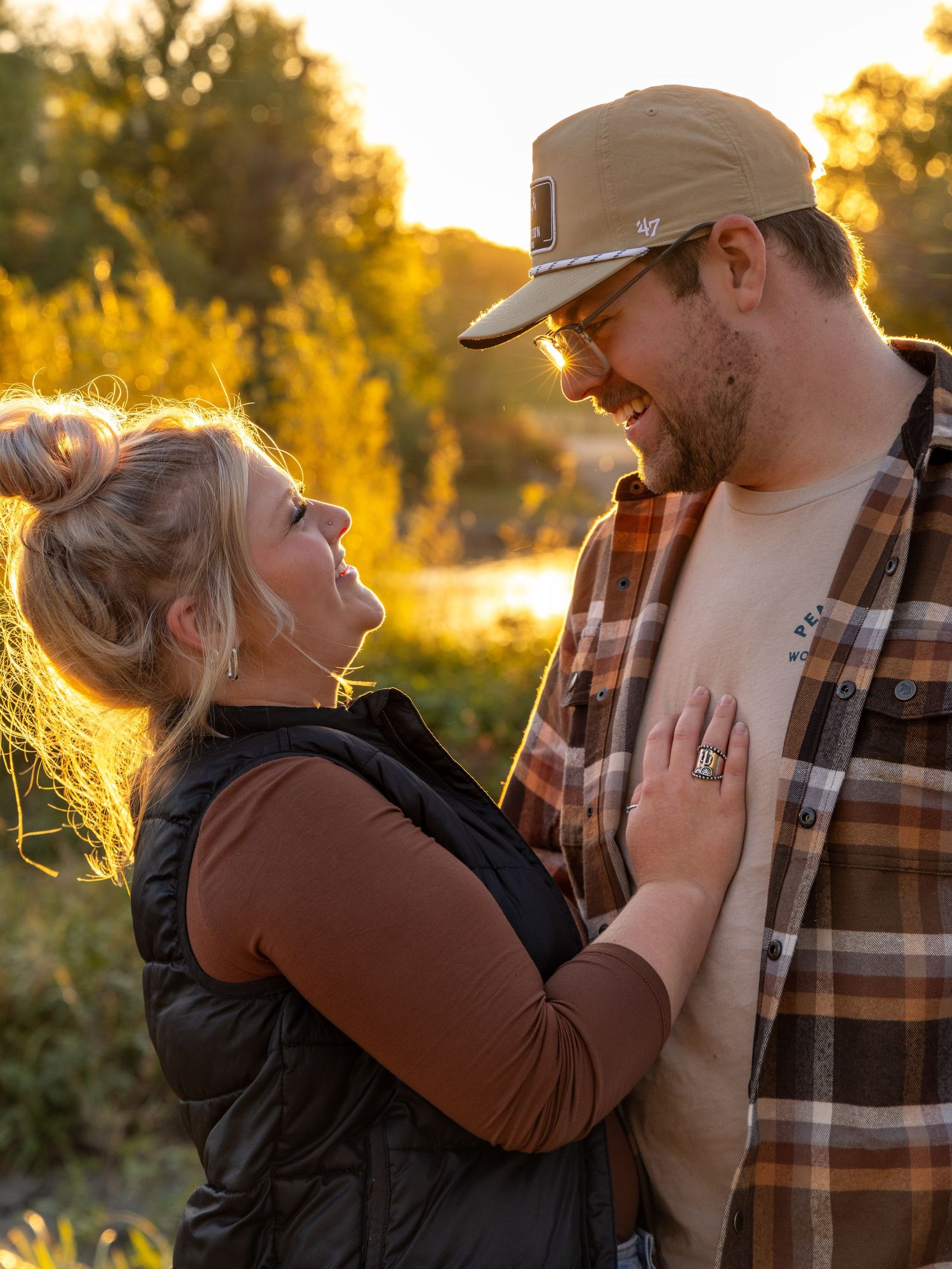 Couple sharing a tender moment at sunset wearing matching plaid and vests.