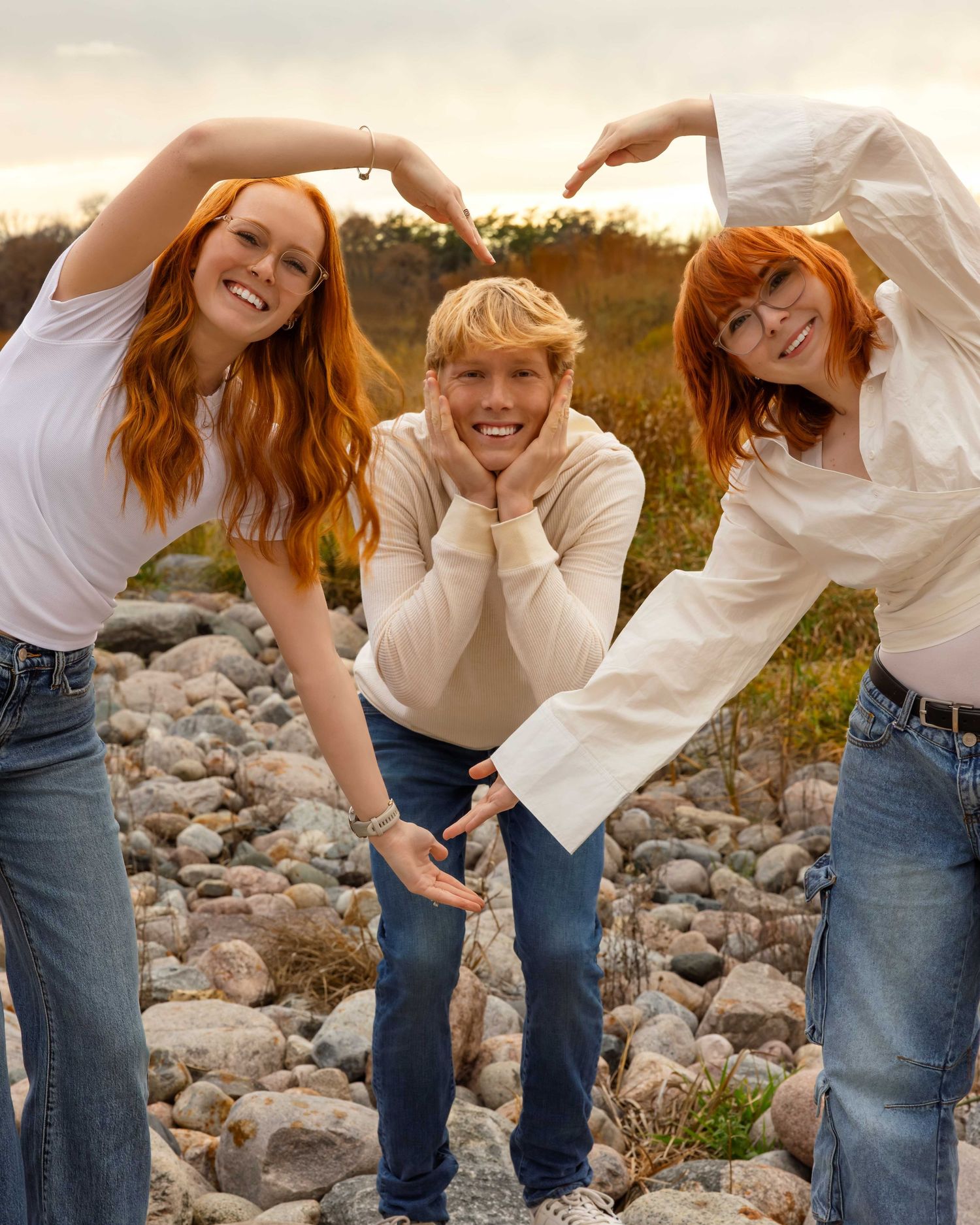 A series of playful poses on rocky terrain at sunset showing movement and joy in casual jeans and white tops.