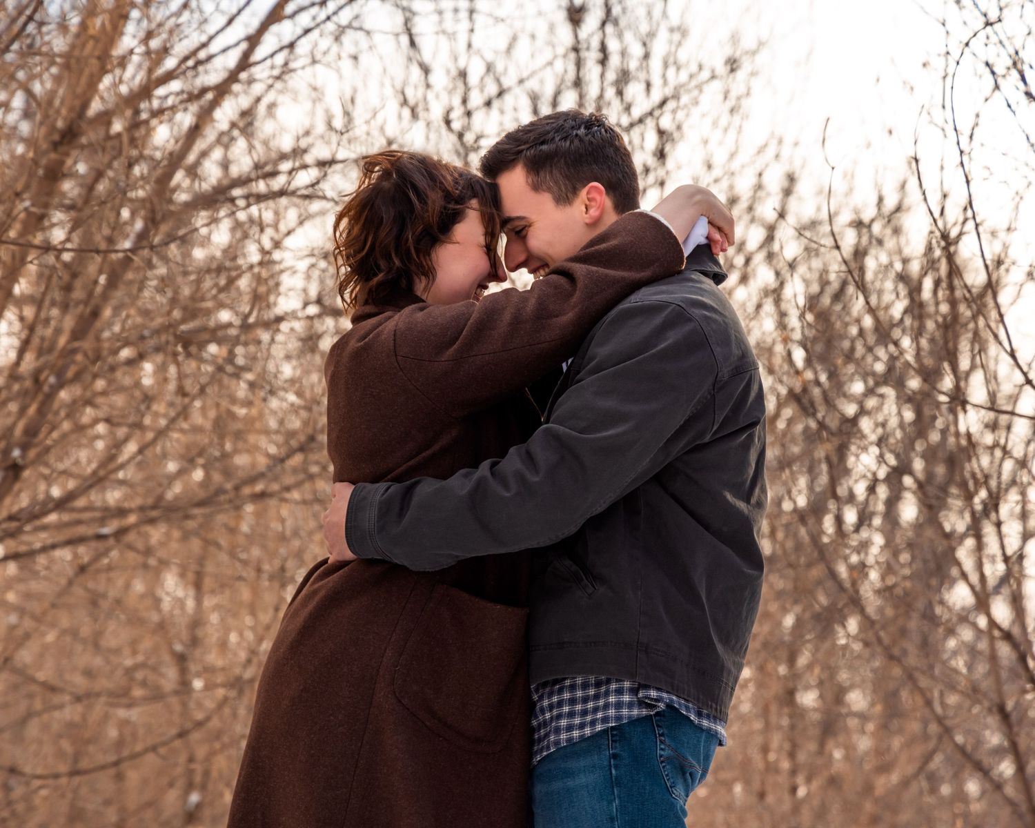 Couple sharing tender moments in a snowy winter landscape at sunset.