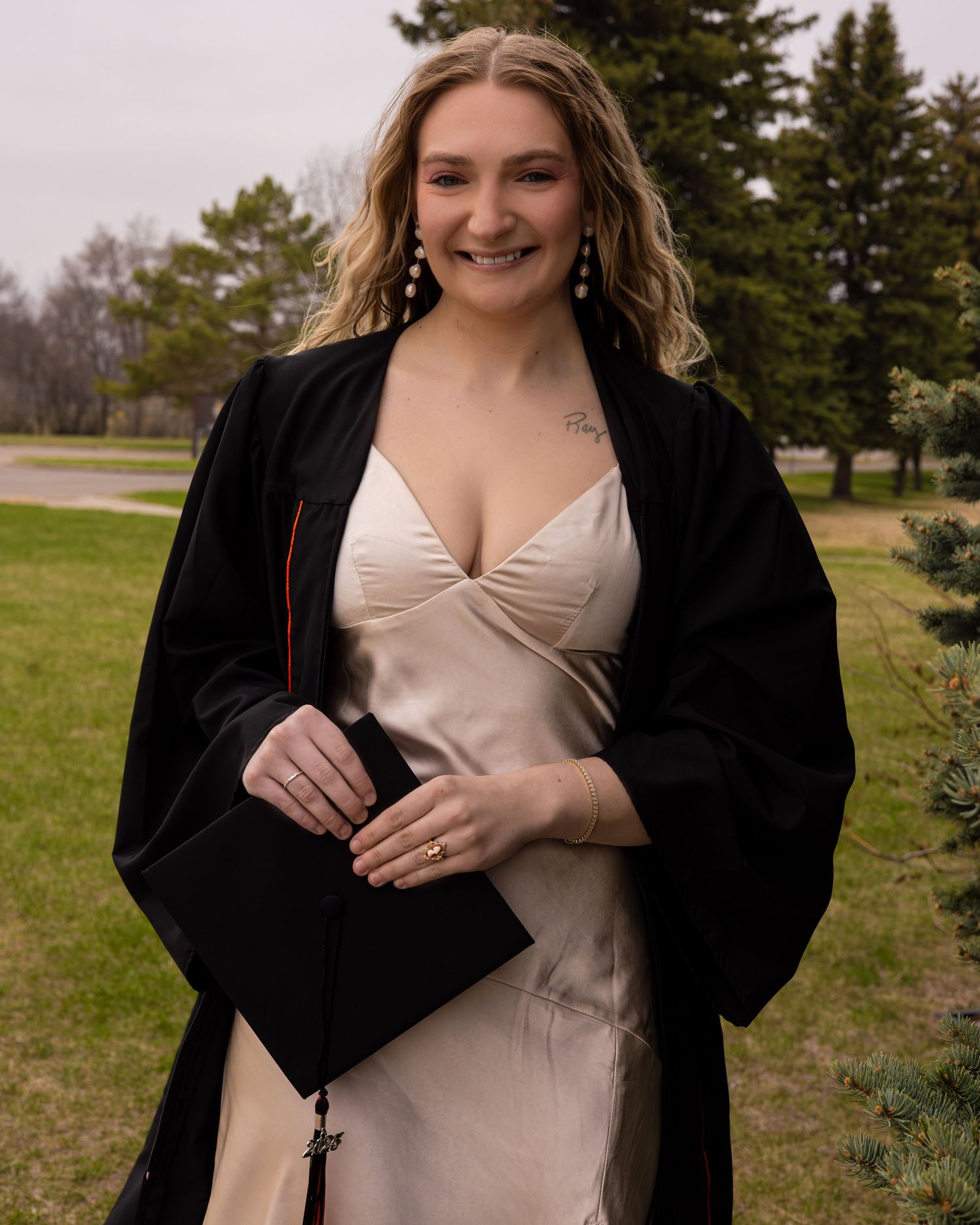 Graduation portraits in beige dress and black gown against natural outdoor setting.