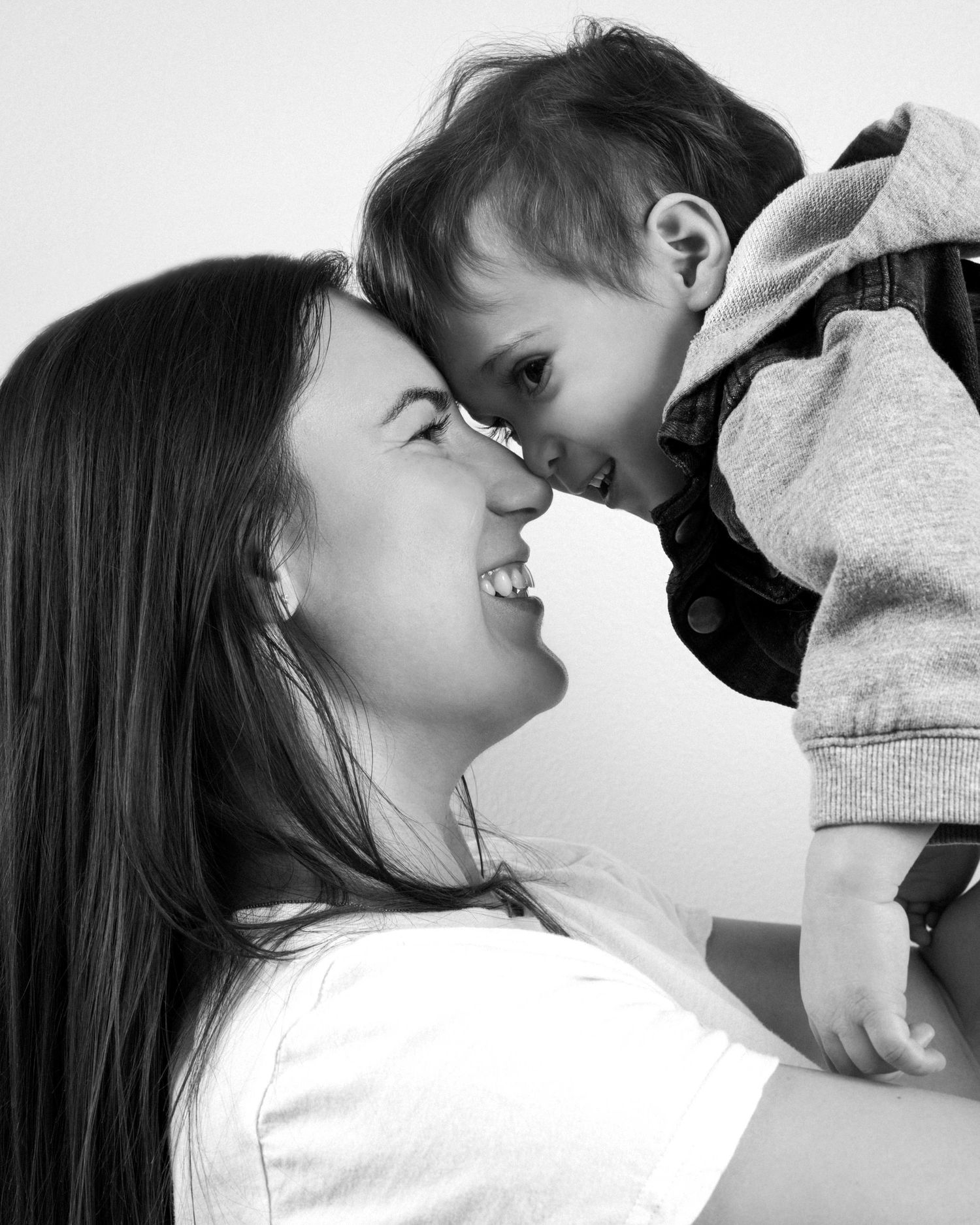 A tender moment between parent and child sharing laughter and affection in black and white.