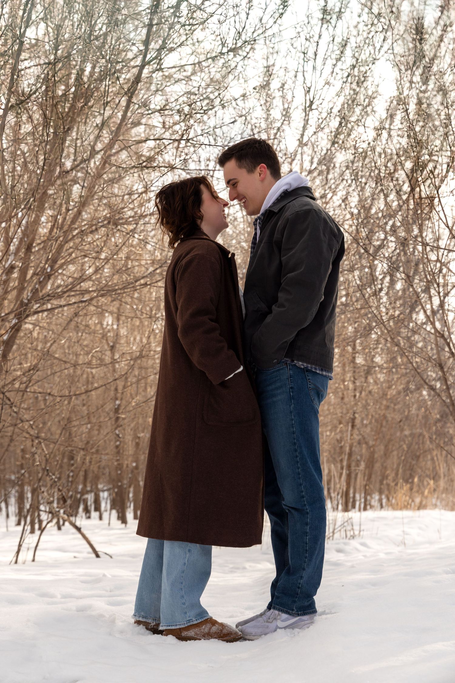 Winter engagement photos showing couple in casual attire against snowy landscape.