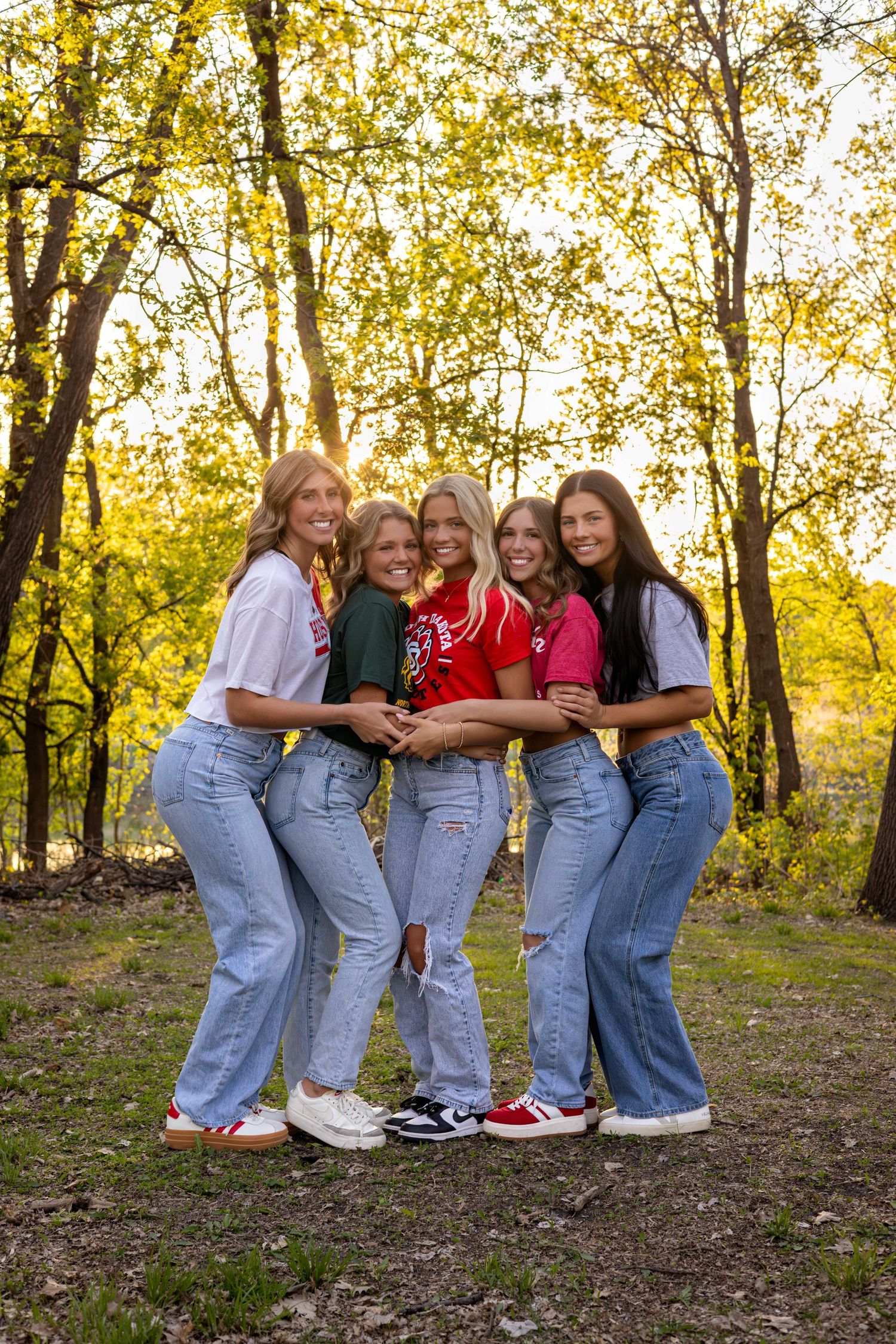 Group wearing matching denim poses together among autumn trees.